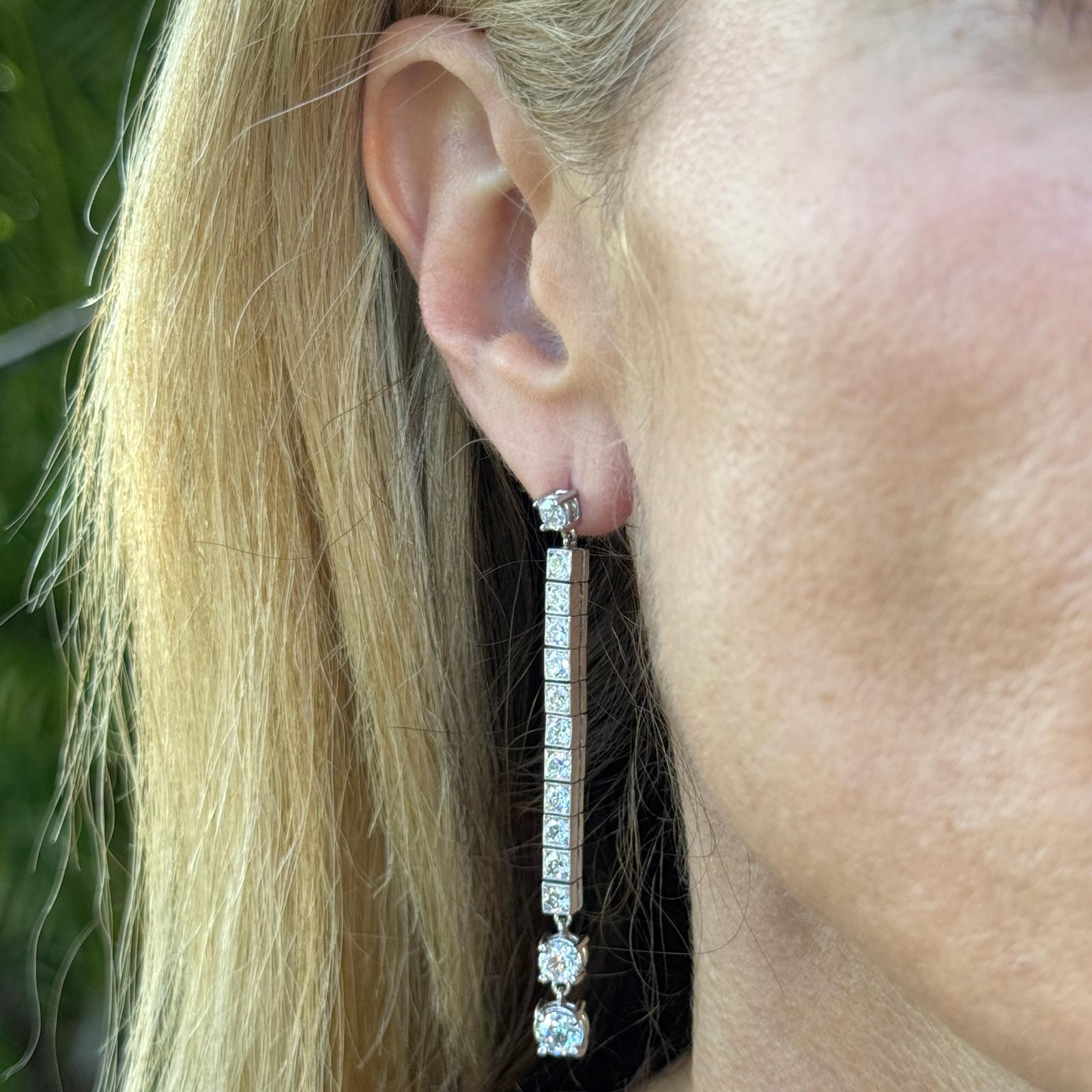 These stunning platinum diamond line drop estate earrings showcase a graceful silhouette adorned with approximately 4.66 carats of Old European Cut diamonds. Each earring features a vertical line design with diamonds, including two larger OECs