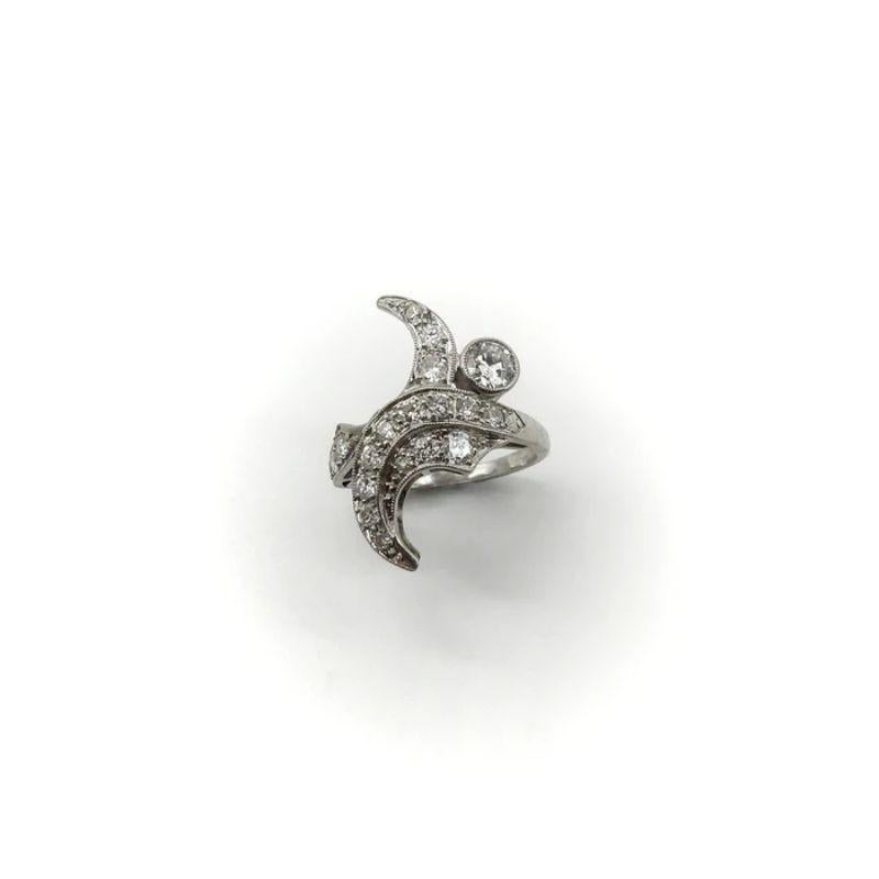 This organic shaped platinum ring dates to the 1950’s, making it a mid-century piece. Its beautiful design could be interpreted in many ways—organic, flowerlike, a French curve. Its central diamond, a 4.5mm round brilliant cut, is surrounded by 18