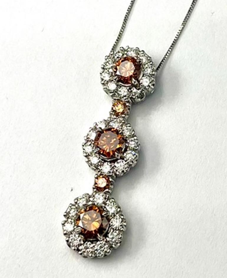 This necklace features three Natural Honey Color Diamonds that weight .97Ct, .79Ct and .78Ct each.  Each diamond is surrounded by a halo of natural white diamonds and is separated by 2 smaller natural honey color diamonds. This pendant drops down