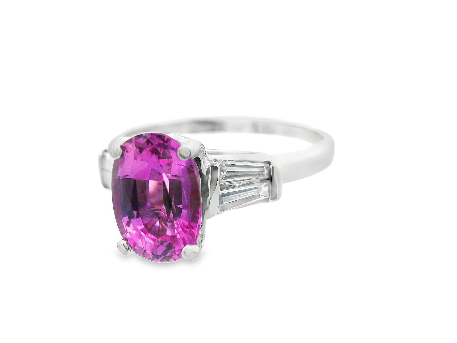 Questo splendido anello in platino degli anni '50 è realizzato in platino e presenta uno zaffiro rosa vivido con spalle affusolate di diamanti a baguette. Lo zaffiro rosa è un taglio ovale da 2,17 carati con una profondità e un colore meravigliosi.
