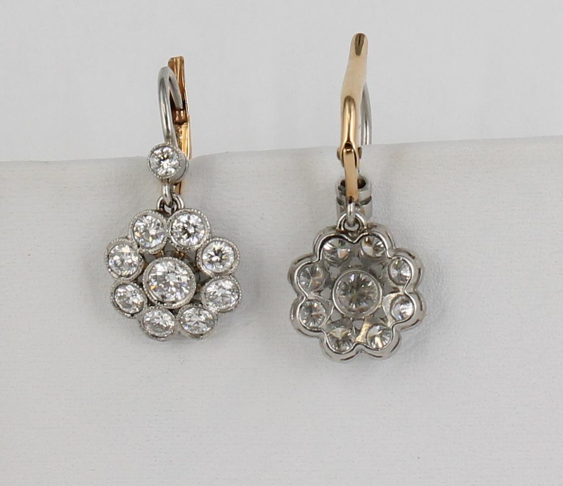 These platinum earrings from the 1930's feature 1.42 carat total weight of round bezel-set diamonds designed to resemble a flower.  They are 1/2 inch in diameter and 3/4 inch long including the lever clasp, the back of which is 18 karat yellow gold.