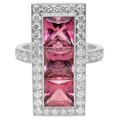 Anello aureolato in platino con tormalina rosa taglio principessa e tre pietre di diamanti