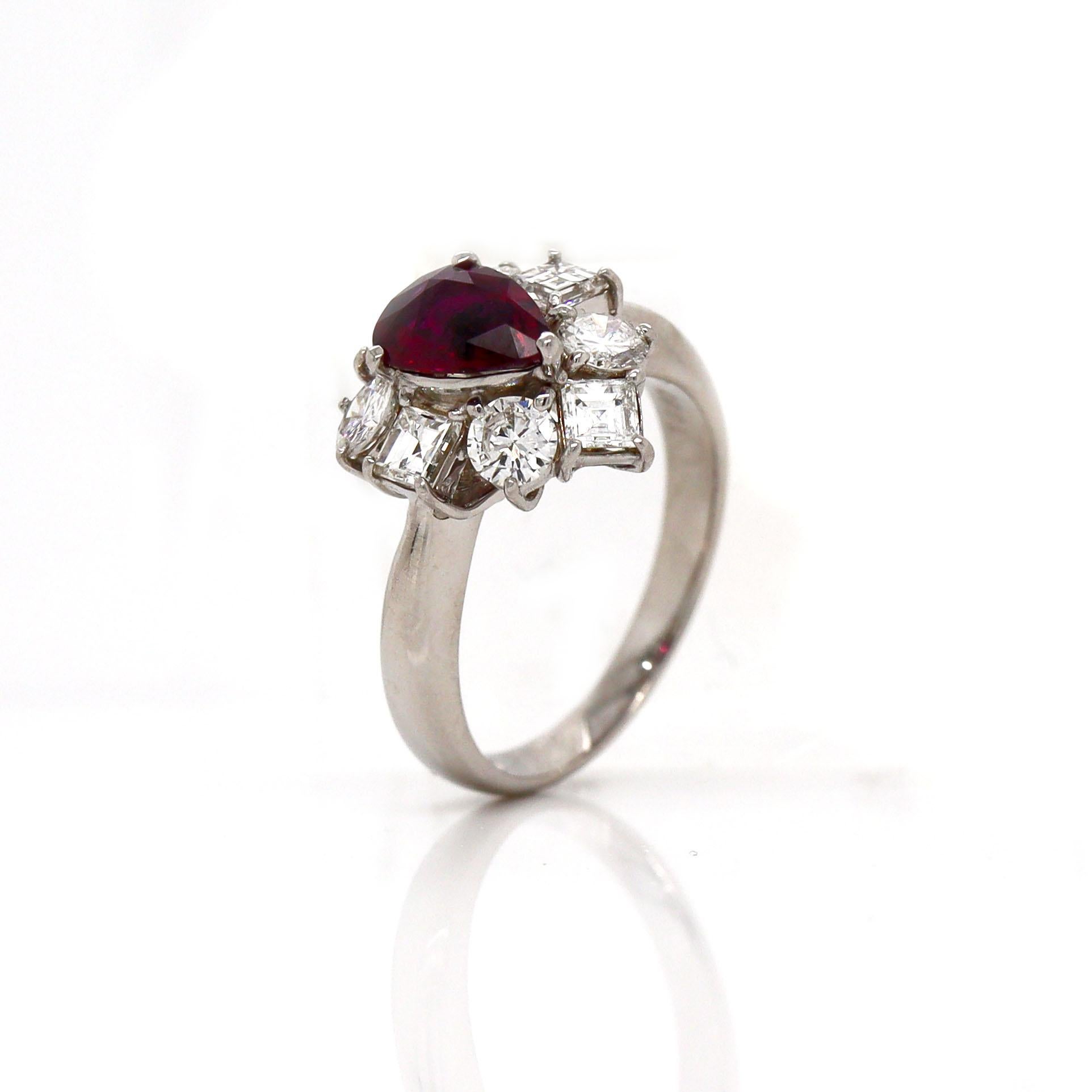 Platinum PT900 Ruby and Diamond Ring

This platinum ring features a stunning pear-cut ruby at its center, radiating a deep, vibrant red that draws the eye with its rich, fiery hue. Surrounding the ruby are a dazzling array of assorted square Asscher