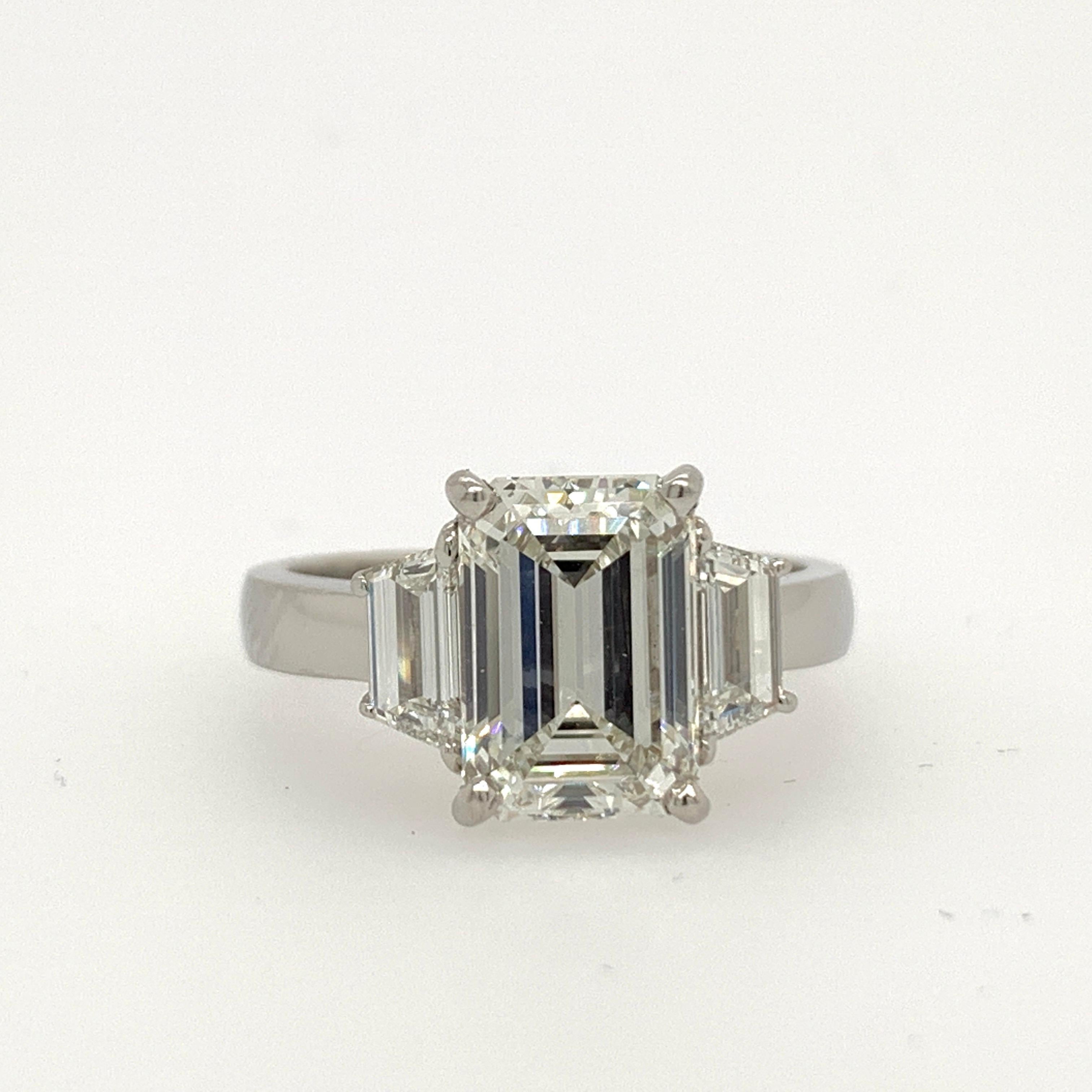 Platinum Ring set with a rectangular emerald cut certified diamond flanked with a matching pair of step-cut trapezoids (weighing 0.80 carats) with similar color and clarity. 

Total weight is 3.32 carats.

The centerstone is rectangular and almost