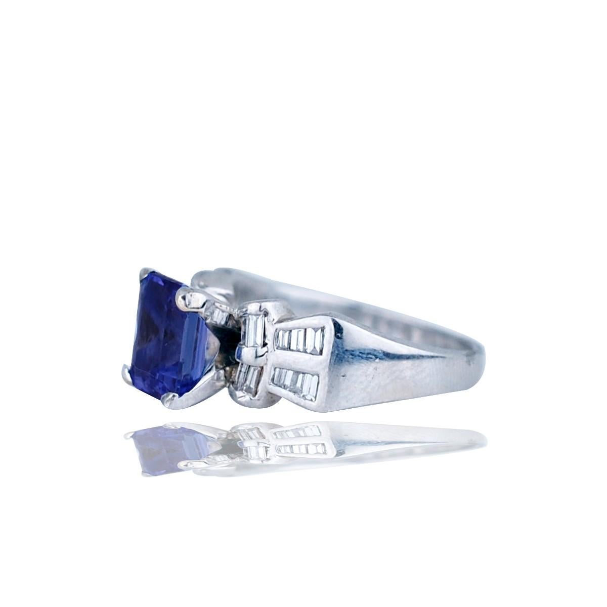 Platinum Ring, Bow-Tie Styled With Baguette Diamond & Tanzanite 
Center Emerald Cut, Tanzanite measuring 8.30 x 6.50 x 4.84 mm, weighing approximately 2.60 carat. 
20 Baguette diamonds set in channel are flanked on either side of ring. Hallmarked
