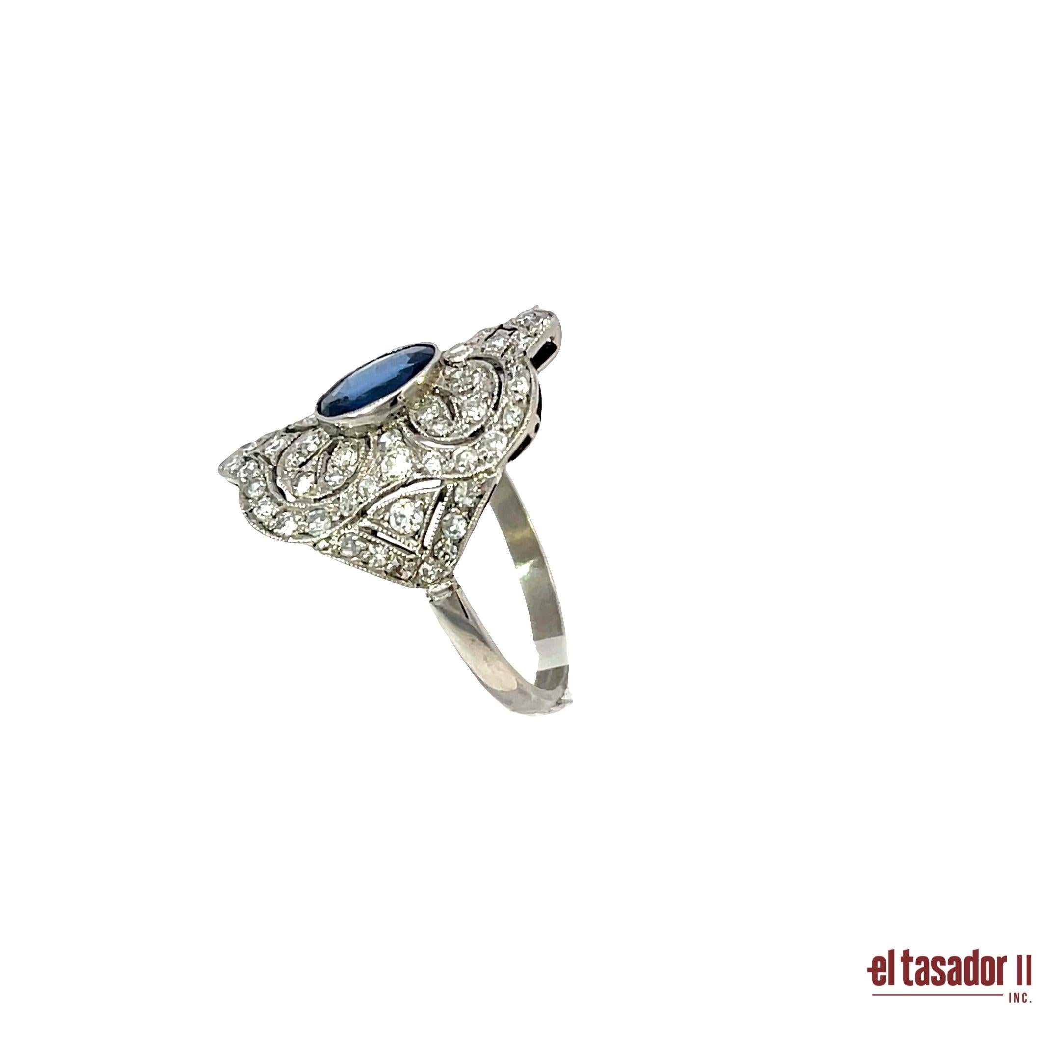 Cette bague en platine, pesant 6 grammes, met en valeur un saphir ovale de 1,40 carat d'un bleu éclatant, serti au centre d'un motif ajouré complexe. Autour du saphir, des diamants taille brillant totalisant 0,98 carat sont soigneusement disposés