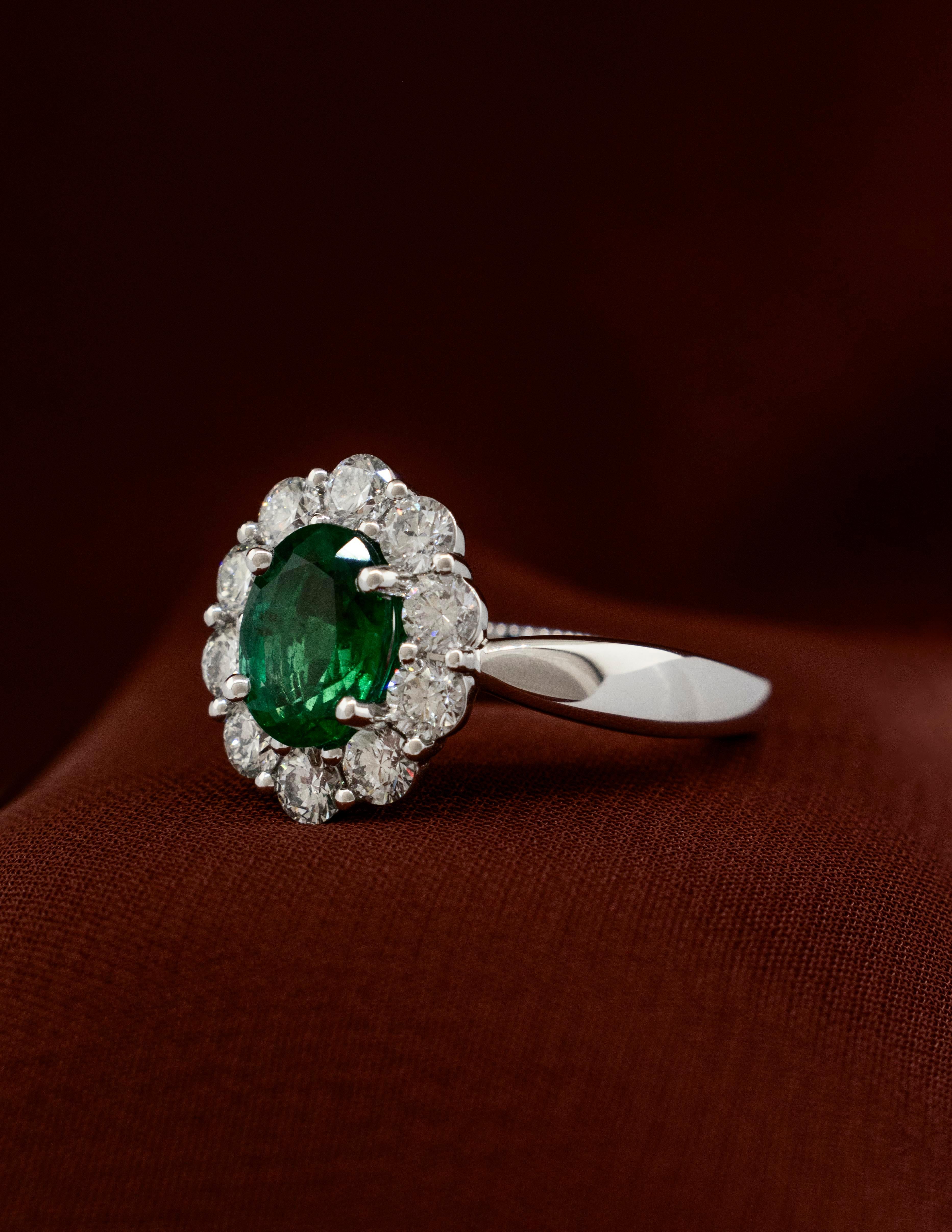 Oval Cut Platinum Ring with 1.56 carat Oval Emerald surrounded by Brilliant Diamonds For Sale