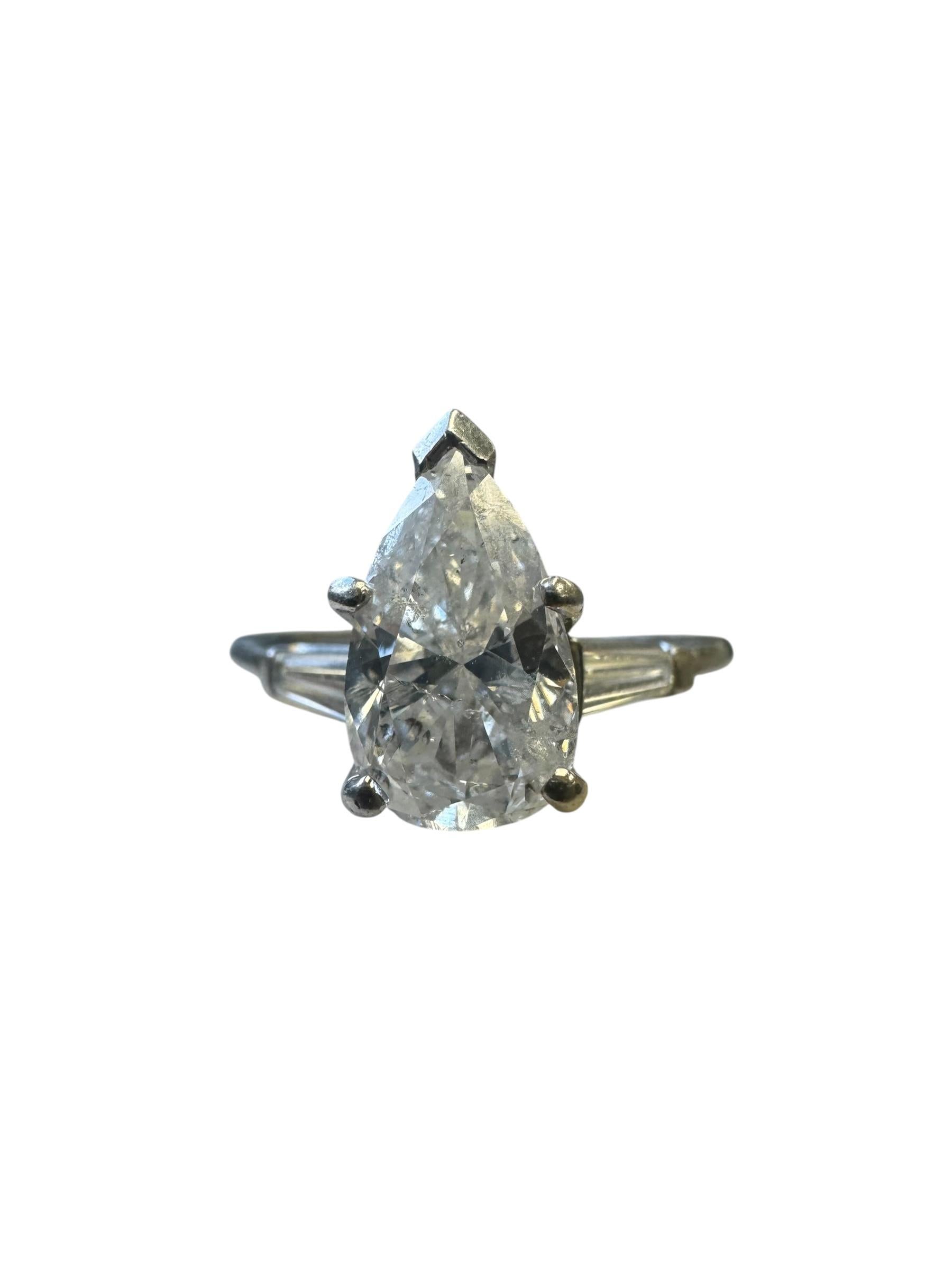 A classic platinum diamond ring centering a beautifully proportioned pear-shaped diamond weighing approximately 1.60 carats. The diamond is set in a secure five-prong setting, showcasing its elegant elongated silhouette. Flanking the center stone