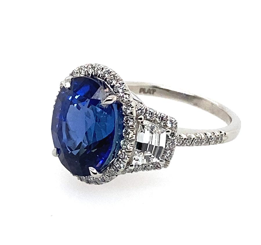 Platinum ring with GIA and GRS certified 9.56 carat, oval cut, Royal Blue Ceylon Sapphire, set with two trapezoid cut diamonds weighing 0.76 carats and 0.52 carats of round brilliant diamonds.