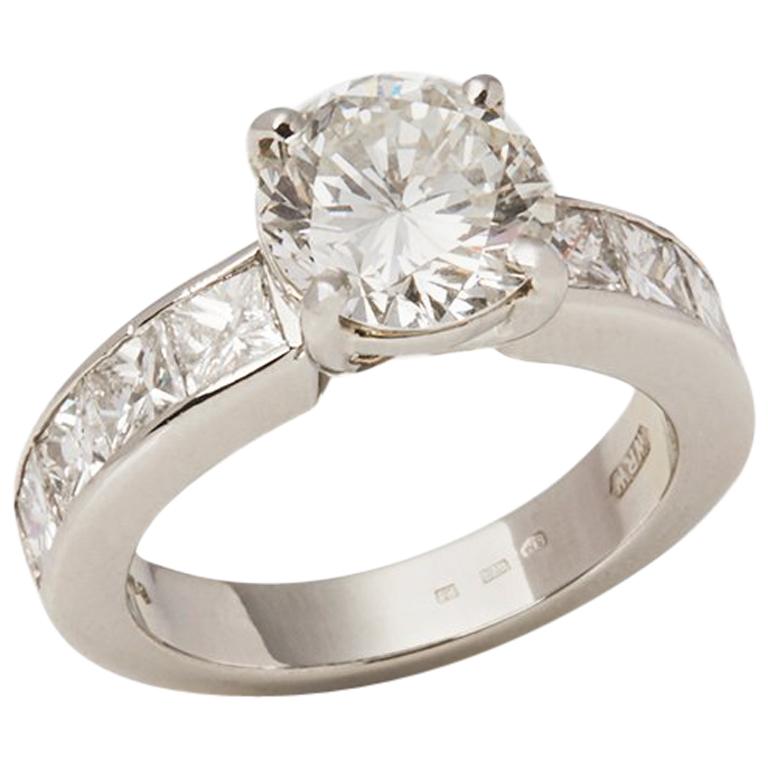 This Engagement Ring features a central round brilliant cut Diamond of 2.20ct colour J, clarity VS2 with 8 princess cut Diamonds on the shoulders of 1.50ct total colour G/H, clarity VS, made in Platinum. The Ring sizes are U L, EU 51 1/2 and US 5