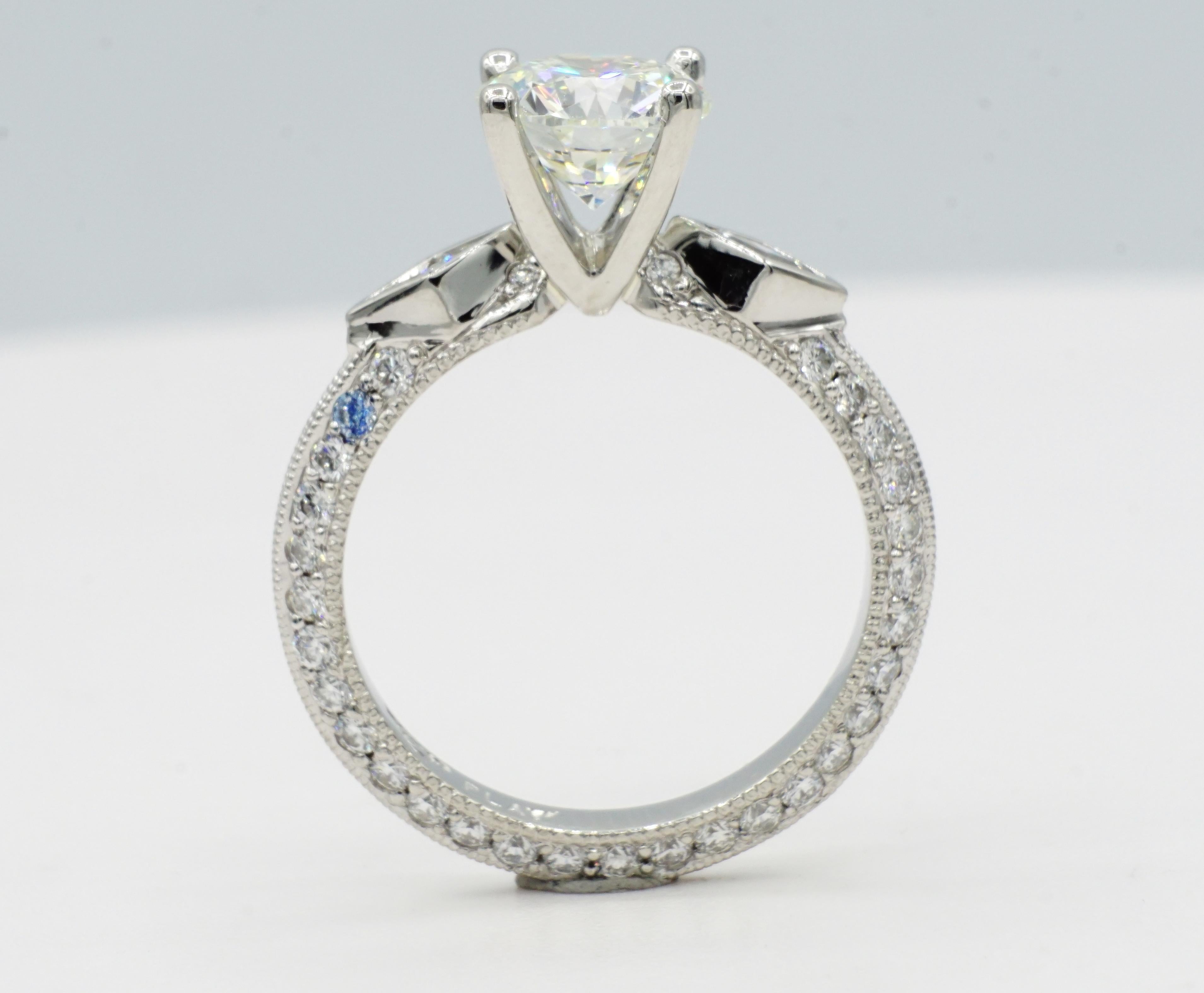 Beautiful platinum engagement ring with 1.59ct round brilliant diamond that is H color and VS2 in clarity. The center diamond has a very good polish, symmetry, and cut.  The center stone is set in a custom V-shaped setting, accented by two full