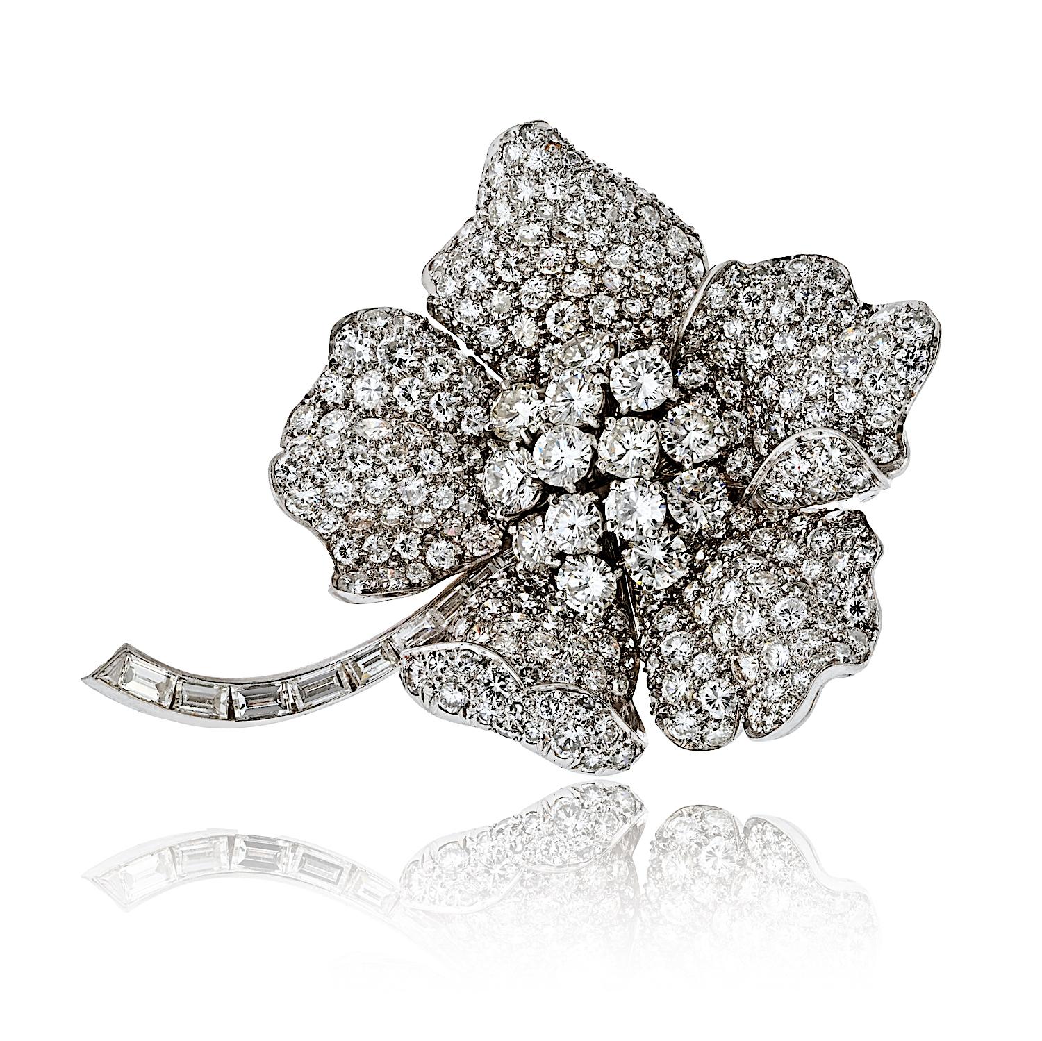 Une broche vintage remarquable, conçue dans la forme élégante d'une fleur, fabriquée en platine et incrustée d'environ 17,00 carats de diamants étincelants. La fleur est composée de diamants ronds brillants, tandis que la tige est ornée de baguettes