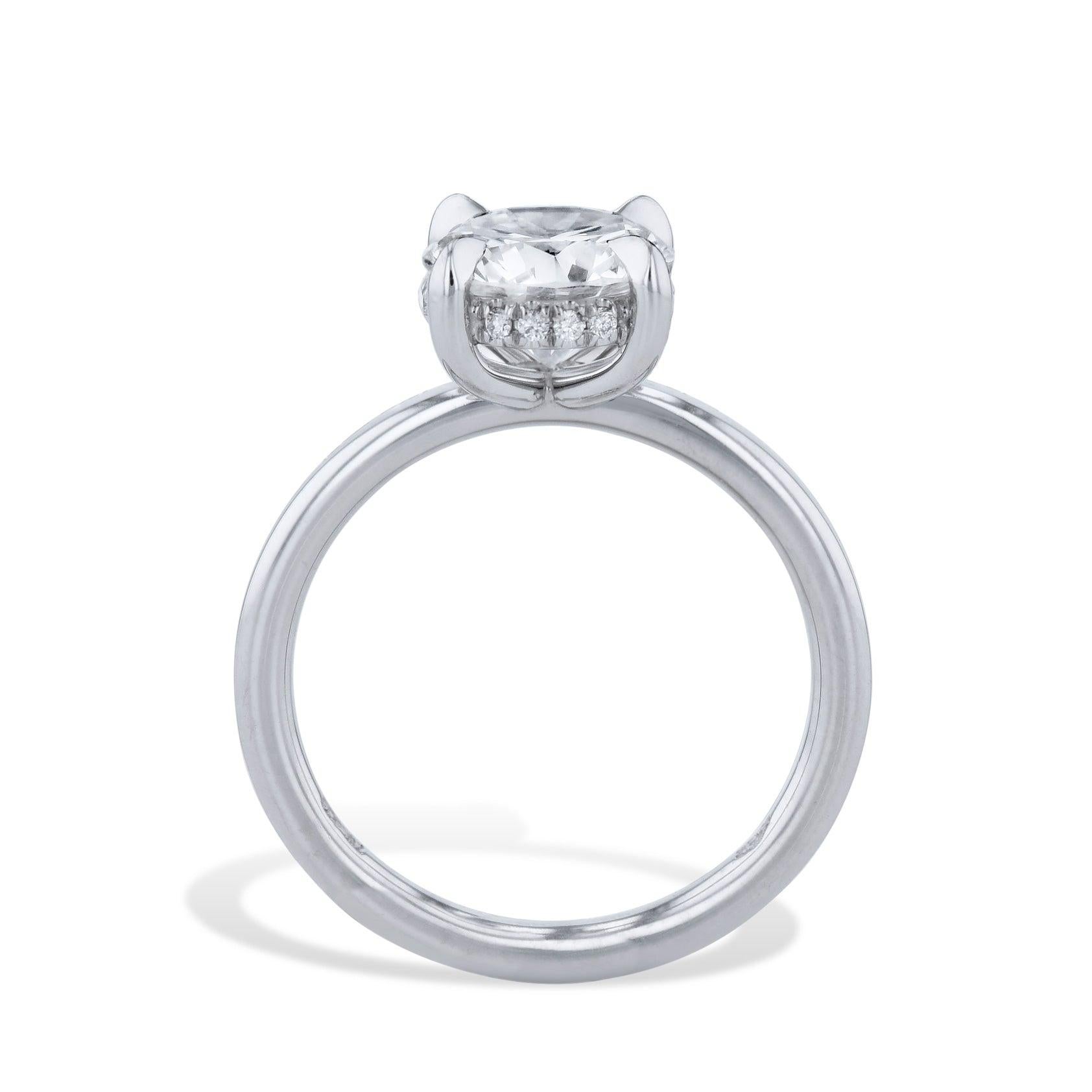 This Platinum Round Diamond Engagement Ring features a stunning Round Brilliant Cut Diamond set in the center, embraced with 16 shimmering 0.07ct F/G VS Pave set stones under the basket. Crafted from high-quality platinum and handmade to perfection,