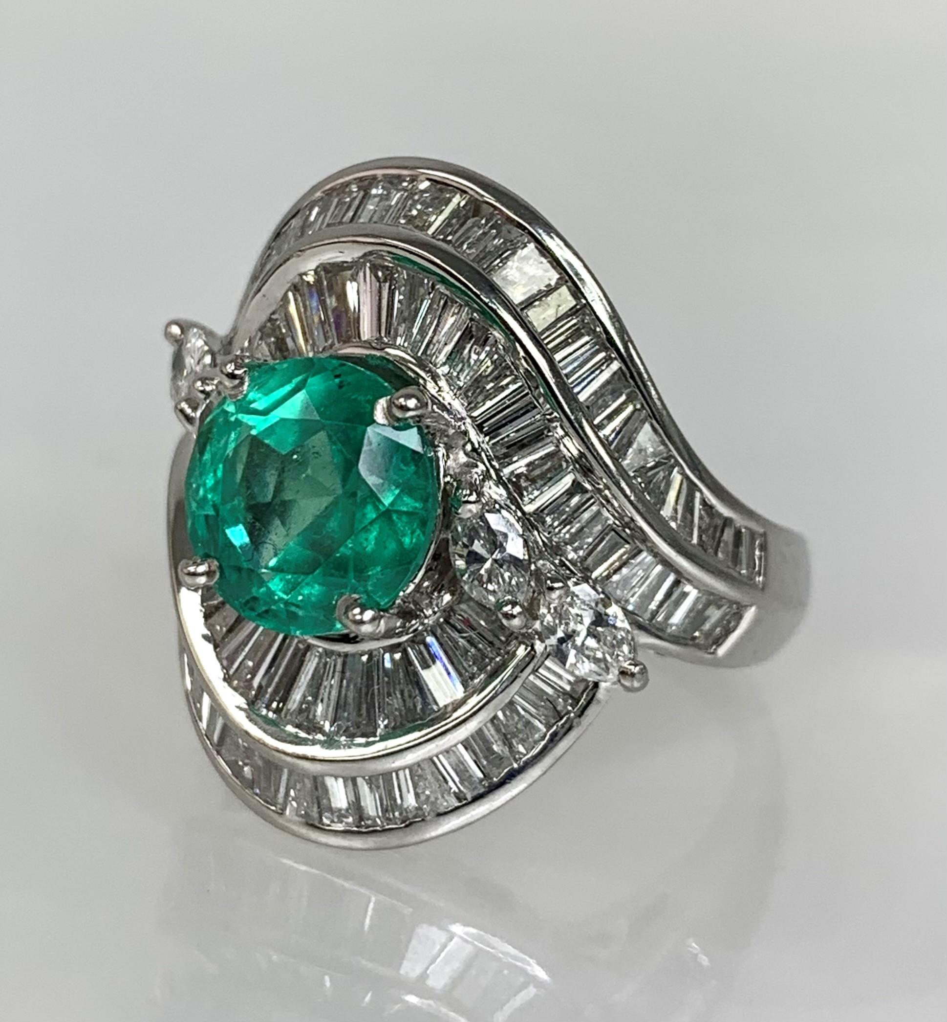 A lustrous and luxurious one of a kind vintage platinum ring featuring a round shaped emerald weighing 2.55 carats surrounded by a medley of multi shaped: baguette, princess cut and round sparkling white diamonds weighing a total of 2.67