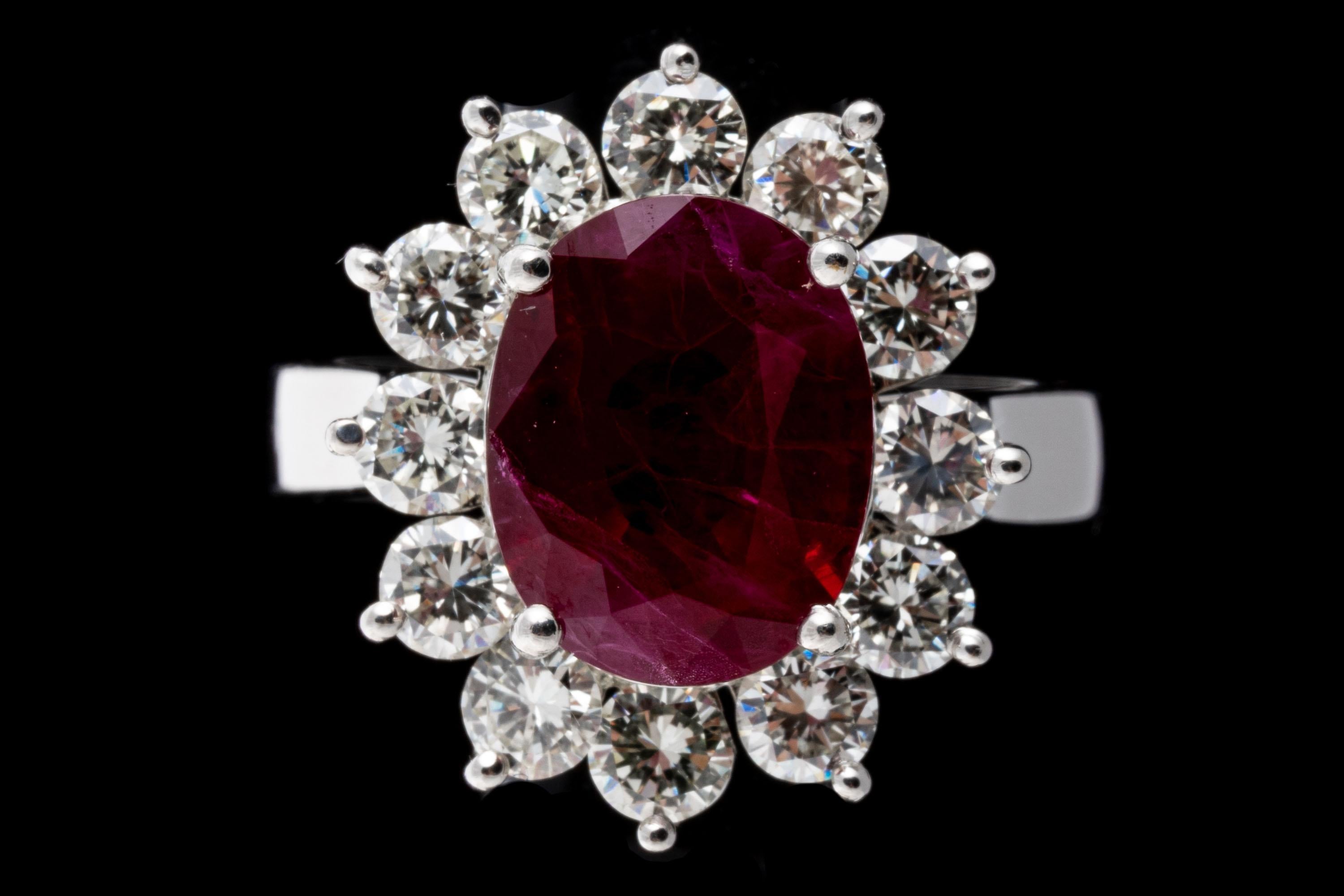 Platinum ring. This gorgeous ring is a Lady Di style, with a faceted oval shape, medium red color ruby center stone, prong set, and approximately 2.82 CTS. Surrounding the stone is a halo of large round brilliant cut diamonds, approximately 0.96