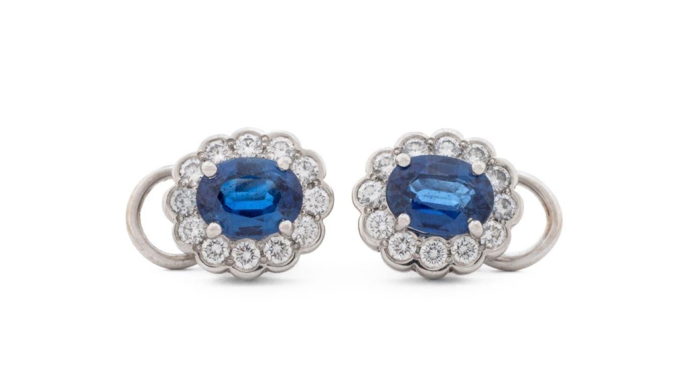 Platinum Sapphire Diamond Earrings, featuring two oval blue sapphires weighing a total of approx. 3.30 carats, further adorned with 24 round brilliant cut diamonds weighing a total of approx. 1.20 carats, worn on the earlobes as clip-ons with omega
