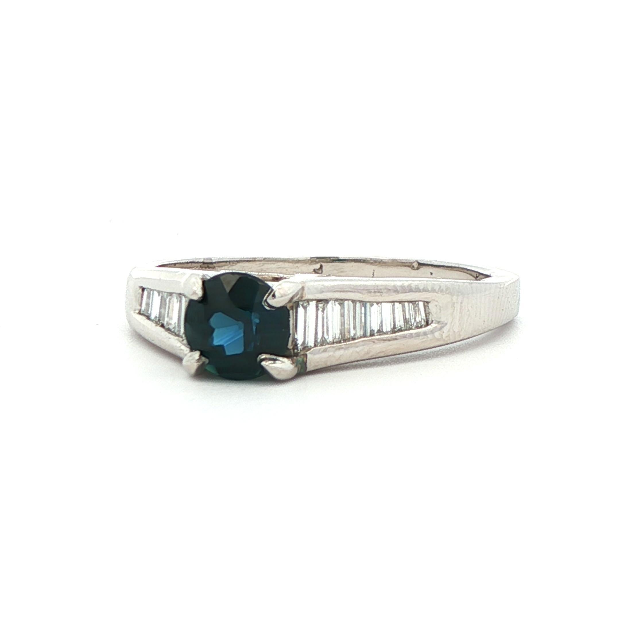 Este impresionante anillo de platino tiene como piedra central un magnífico zafiro azul rodeado de una cascada de brillantes diamantes talla baguette. El zafiro redondo es de un azul intenso, como si estuvieras mirando el cielo nocturno o las