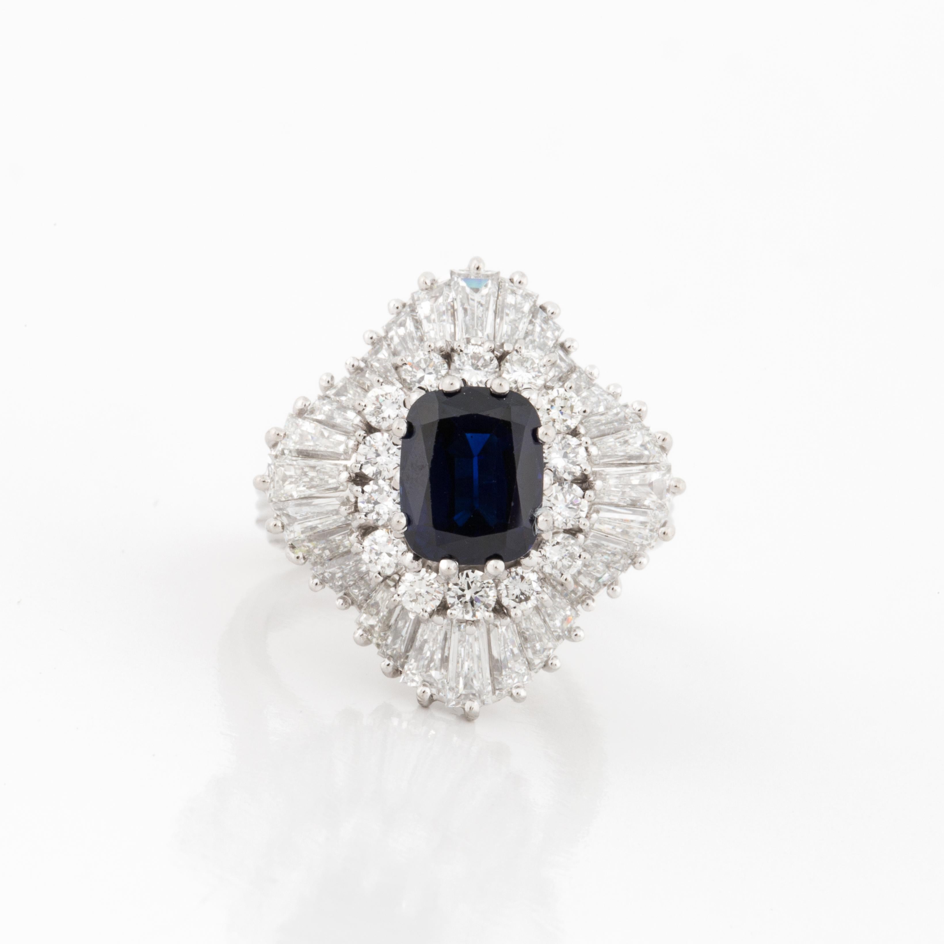 Ballerina style ring composed of platinum featuring a cushion-cut sapphire with round and baguette diamonds.  The sapphire totals 3.35 carats.  There are two rows of diamonds that frame the sapphire, 14 round diamonds that total 0.70 carats and 32