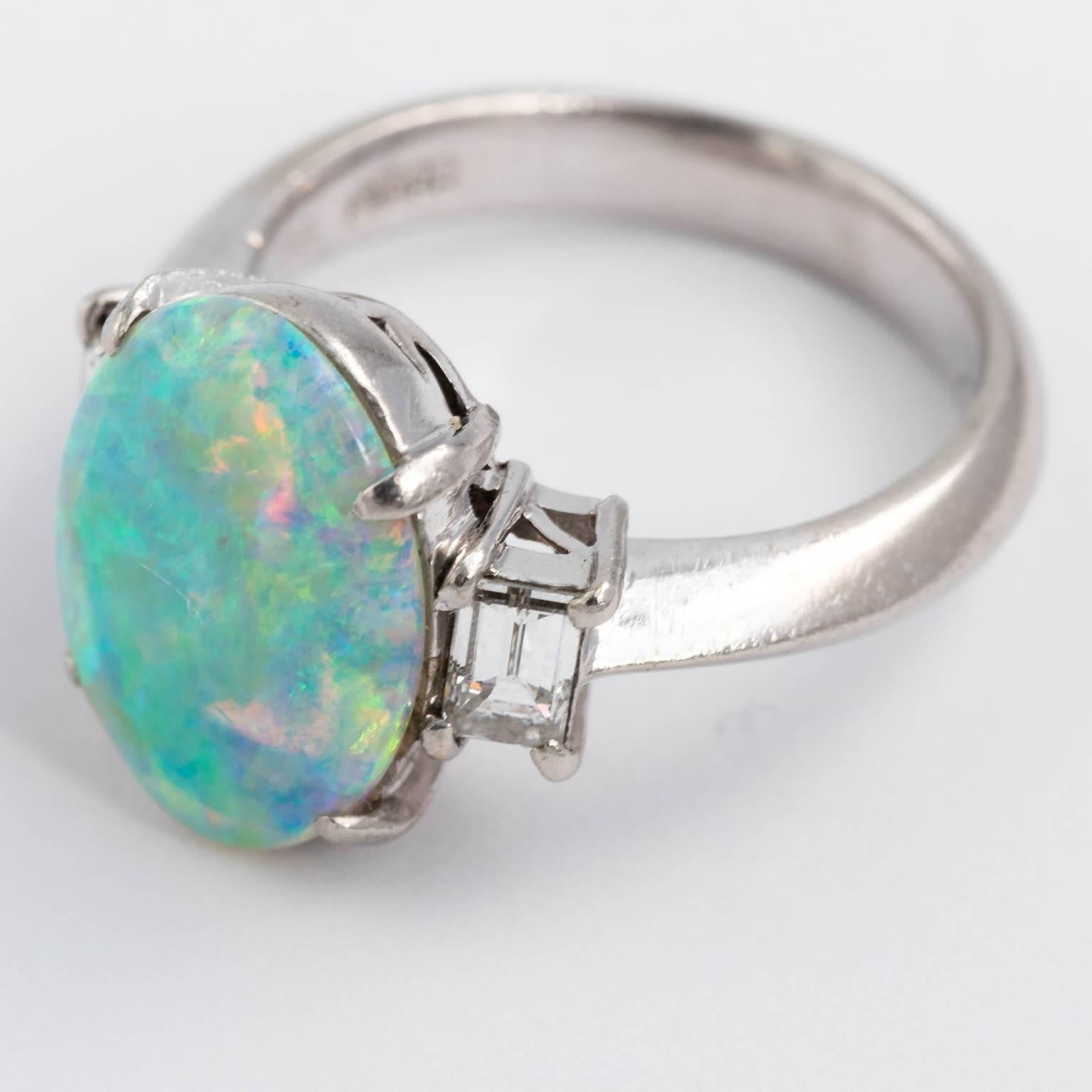 Circa 1980s Opal ring set in mountings with solid platinum band weigh 8.9 grams total flanked by two emerald cut high quality diamonds 1/4 carat each. The opal is 13.5 X 10 mm 2.58 carats. It is highly translucent and having the most beautiful blue,