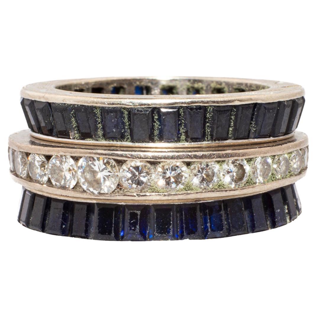 Due fedi eternity di zaffiri incastonati in platino si stringono a una fascia di diamanti taglio brillante incastonati in platino di colore G e purezza S1. L'anello con diamante è di circa 0,40 carati. L'insieme delle fasce di zaffiri è di circa