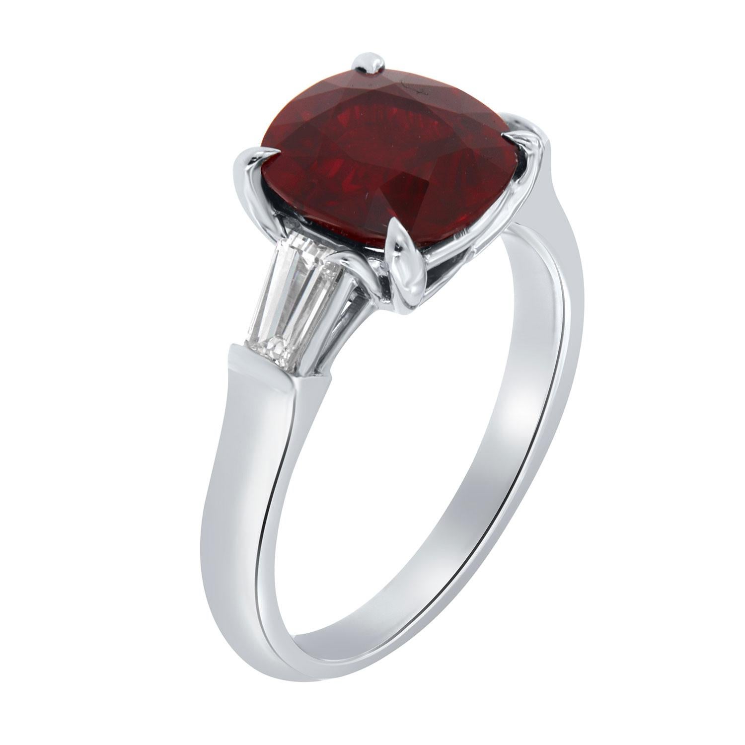 This timeless three-stone platinum ring features a one-of-a-kind square cushion 2.99 carat Red Ruby that exhibits a deep red vibrant color. in excellent luster. The Ruby is flanked by two tapered baguette-cut diamonds in weight of 0.53 carat.