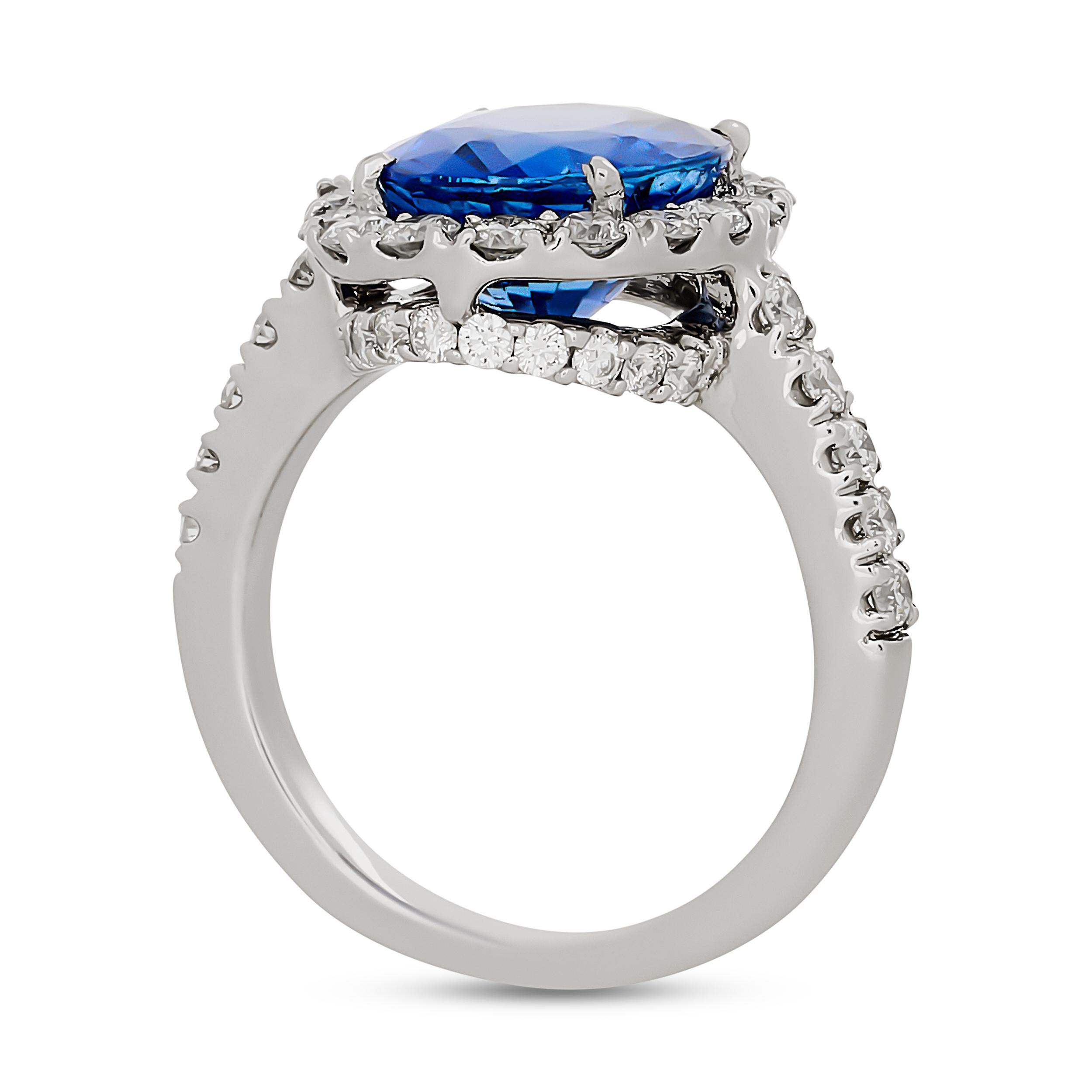 Este exquisito anillo exhibe un magnífico zafiro de Sri Lanka de talla oval, rodeado de un brillante halo de diamantes redondos que también adornan los hombros de la banda de oro blanco.

El zafiro oval central pesa aproximadamente 5,24 quilates, y
