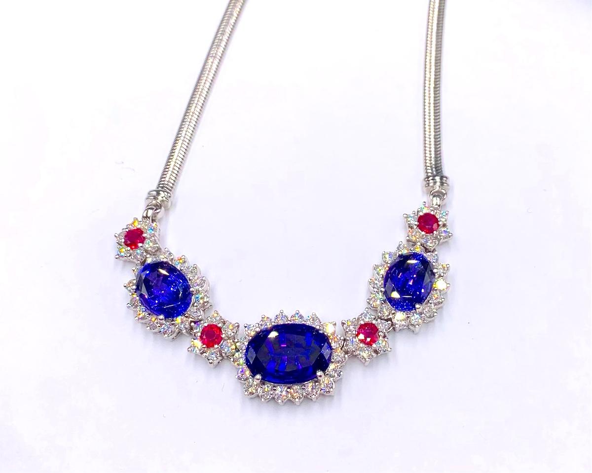 This necklace features a beautiful color combination of gem quality Tanzanites, rubies and diamonds. The center Tanzanite is 14.40Ct, and the next 2 Tanzanites are 7.17Ct and 7.04Ct. It it accented by 4 Rubies of 2.67Ct Total Weight and 70 Natural