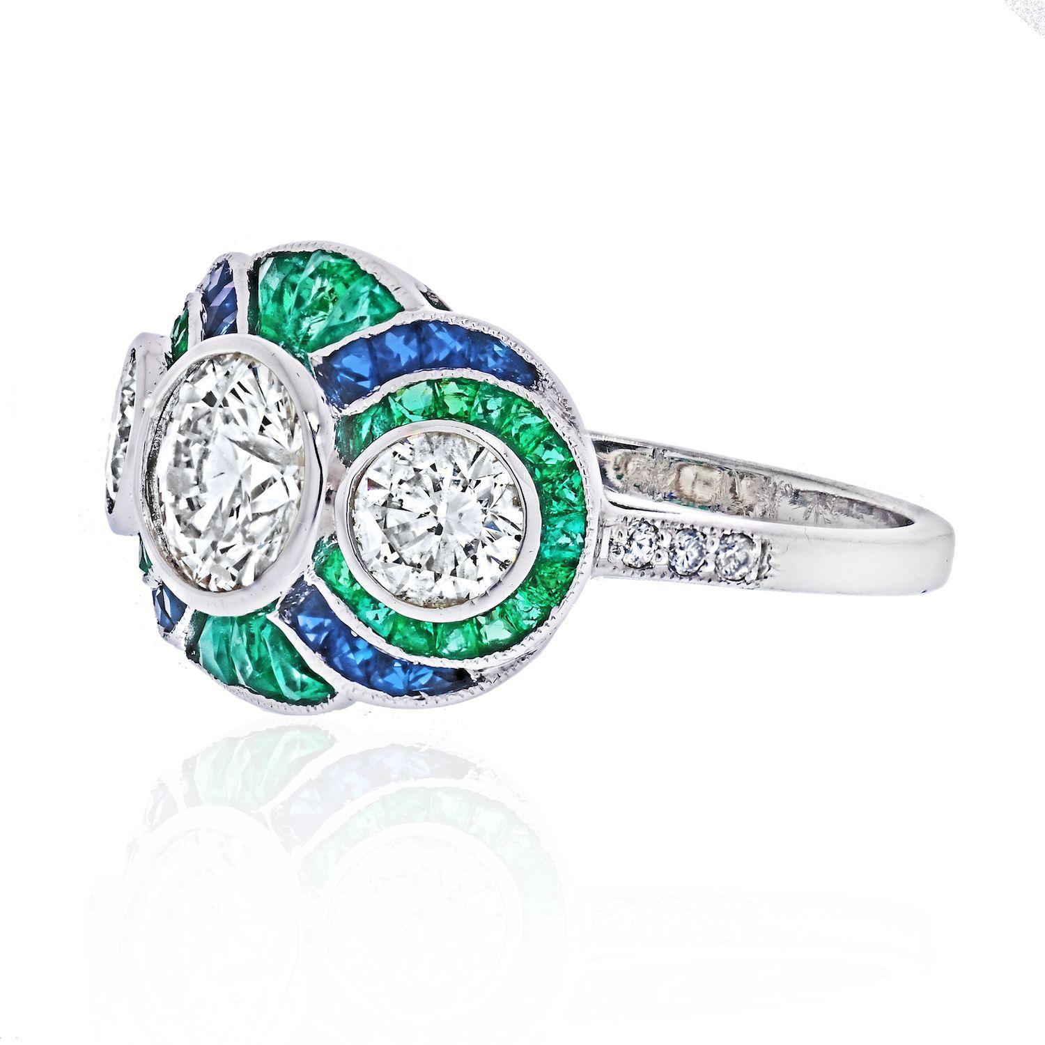 What a lovely three stone diamond engagement ring adorned by sapphires, and green emeralds. This is a newly made but quite vintage looking ring, that was crafted in platinum. Three round cut diamonds are bezel set in the center creating a classic