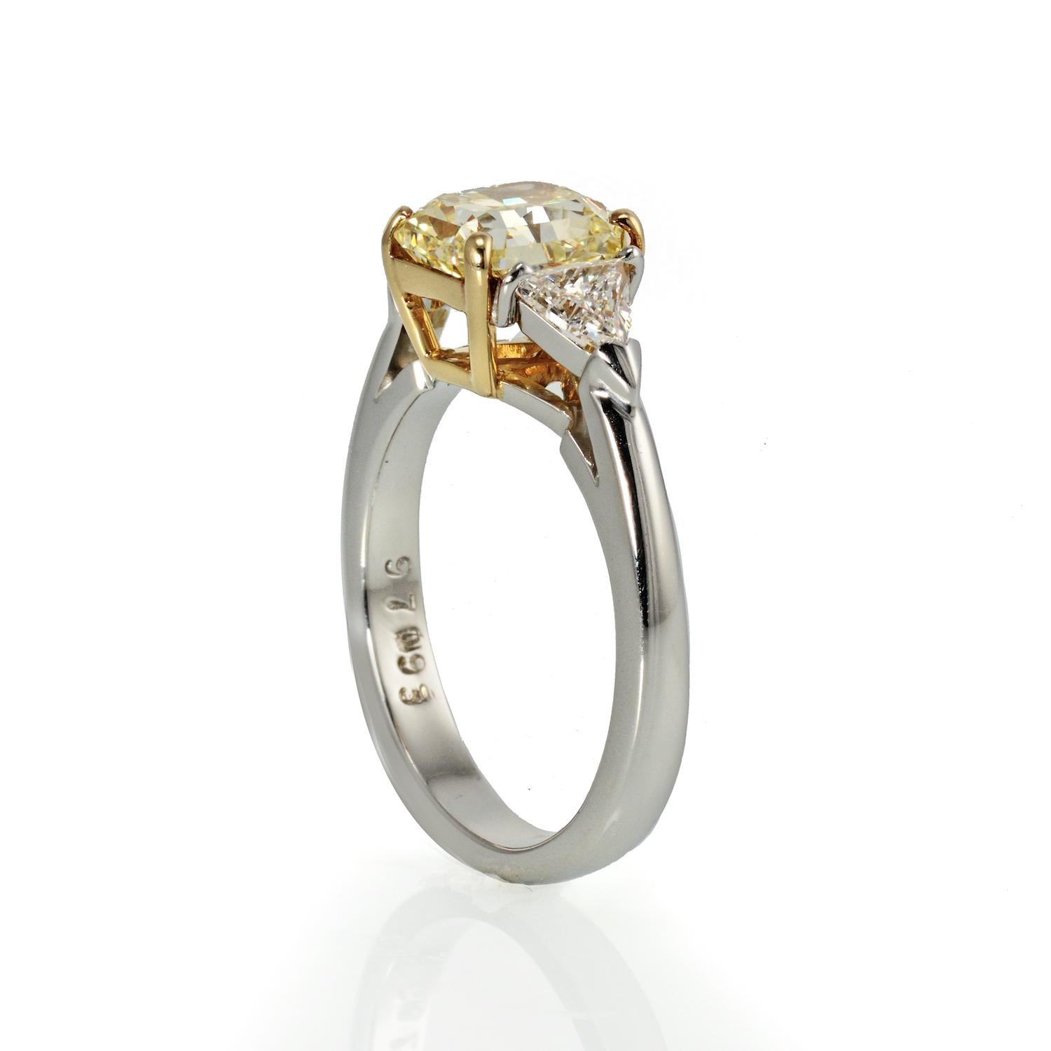 Ladies beautiful platinum and 18kt yellow gold three stone diamond ring featuring a 2.01 carat Radiant-cut Fancy Yellow and (VS1) in clarity. Two trilliant cut diamonds are set on the shoulders totaling 0.50ct total weight of (VS) in clarity and