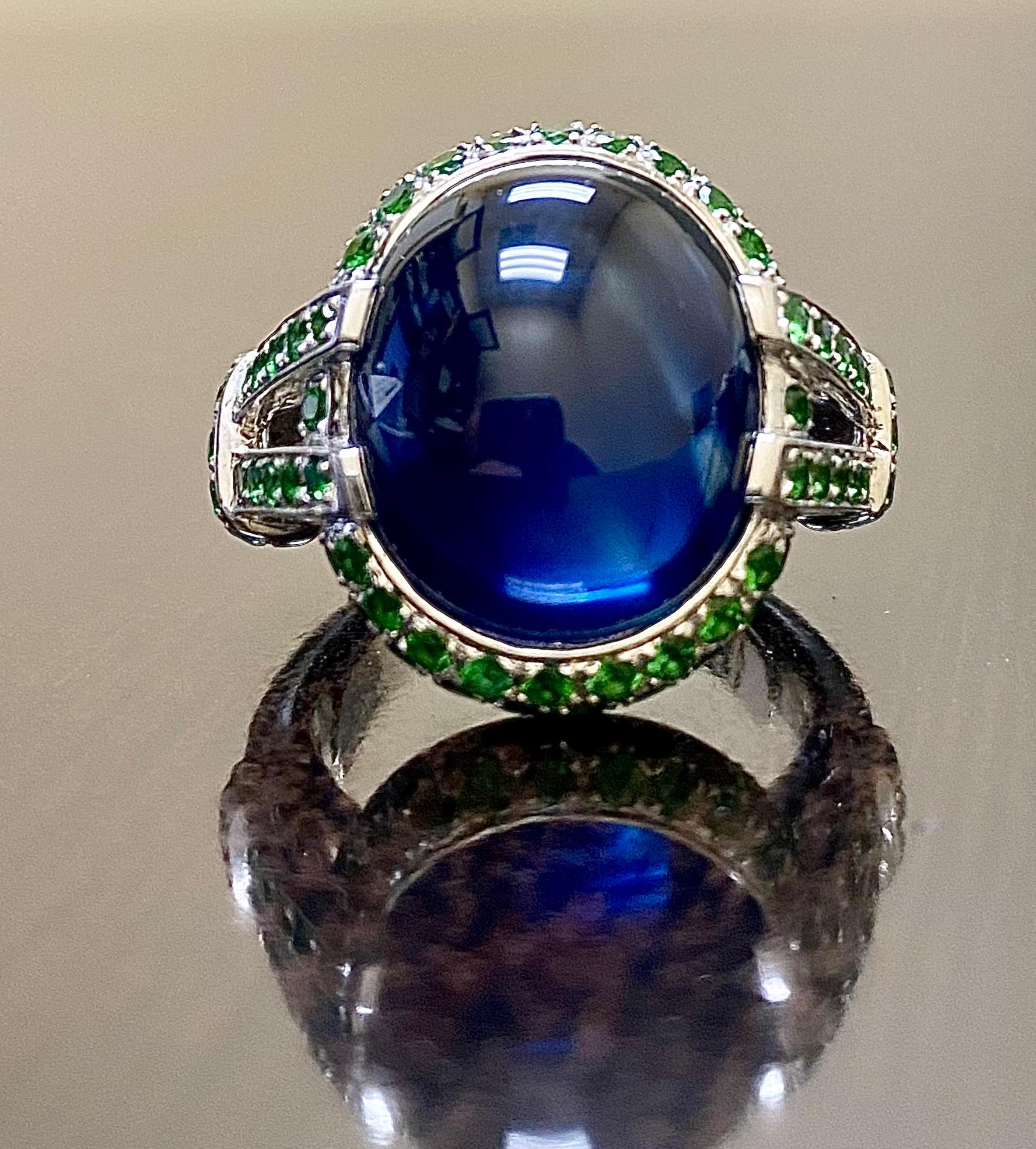 DeKara Design Collection 

Metal- 90% Platinum, 10% Iridium. 

Stones- 1 Genuine Cabochon Blue Sapphire 16.16 Carats, 72 Round Tsavorite Garnets 1.31 Carats. 

Featuring a Dazzling Ring With a Whopping 16.16 Carat Genuine Oval Cabochon Blue