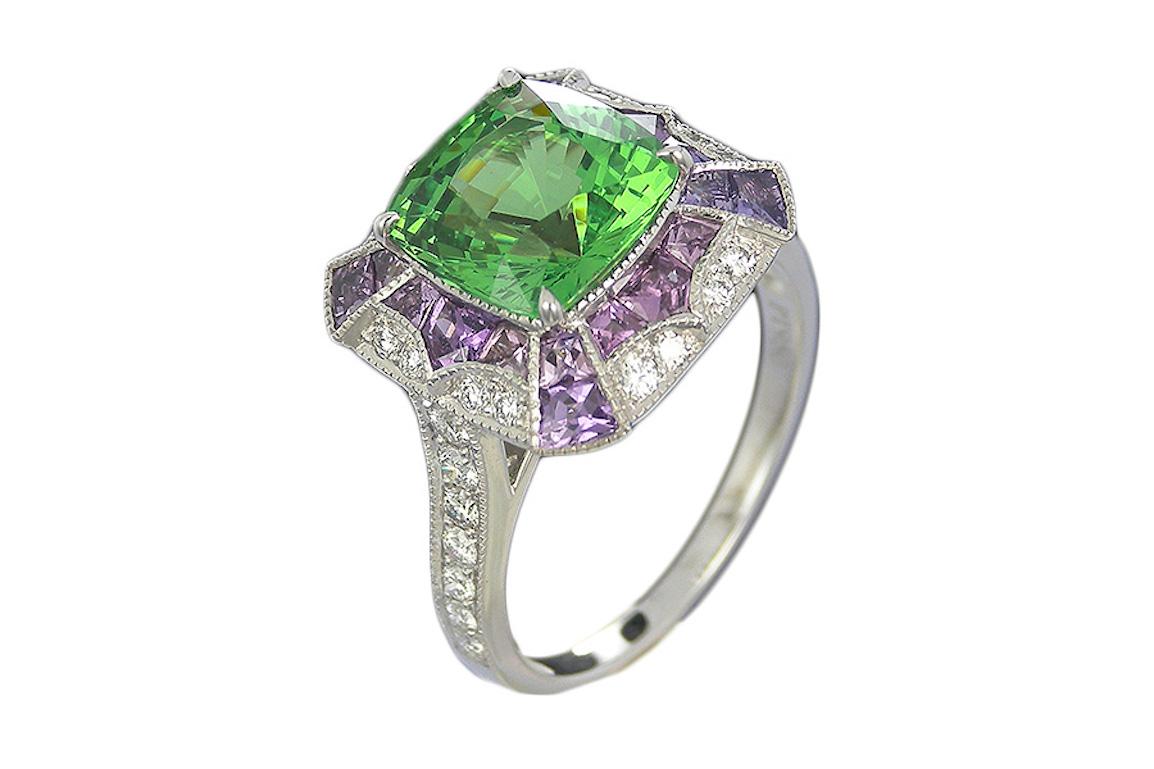 An Eye-catching GIA Certified 3.02 carat Cushion Cut Tsavorite framed in a 4 claw  and surrounded by  a double border of Violette sapphire and Diamonds and further embellished by diamond line shoulders.​
A fine milgrain design embellishes the edges