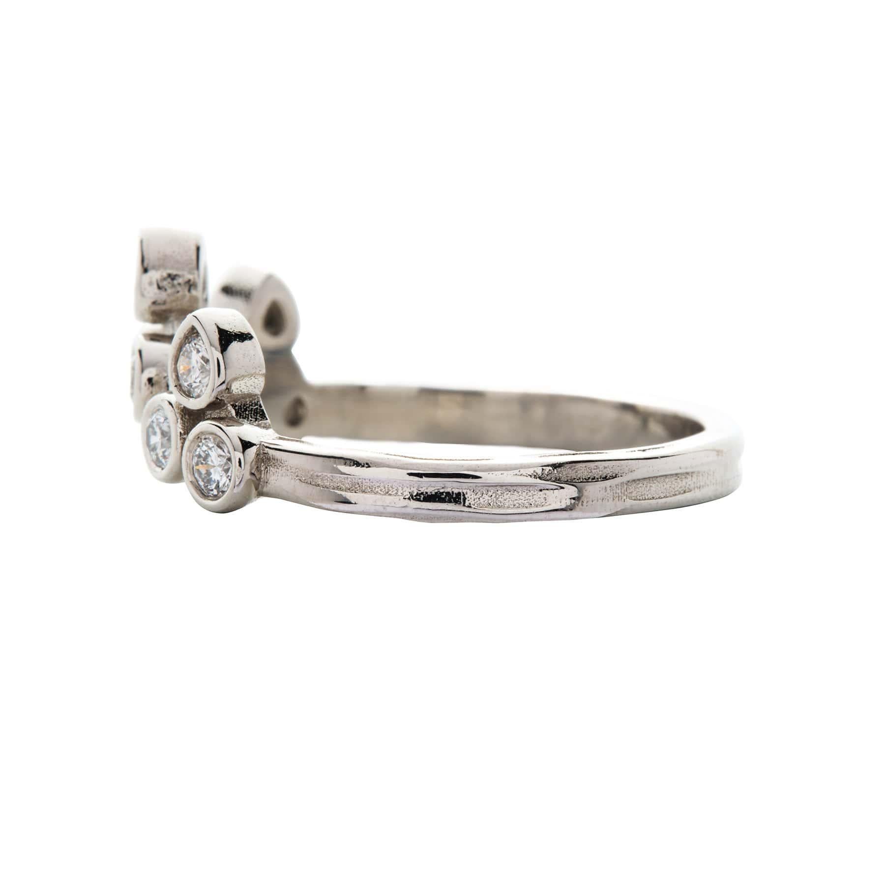 Nine 2.2mm round brilliant cut diamonds set in platinum bezel settings dot the finger in the shape of a tiara. The top 3 settings are pear-shaped, with their points turned out. With its graceful curve, this power ring can be worn in either direction