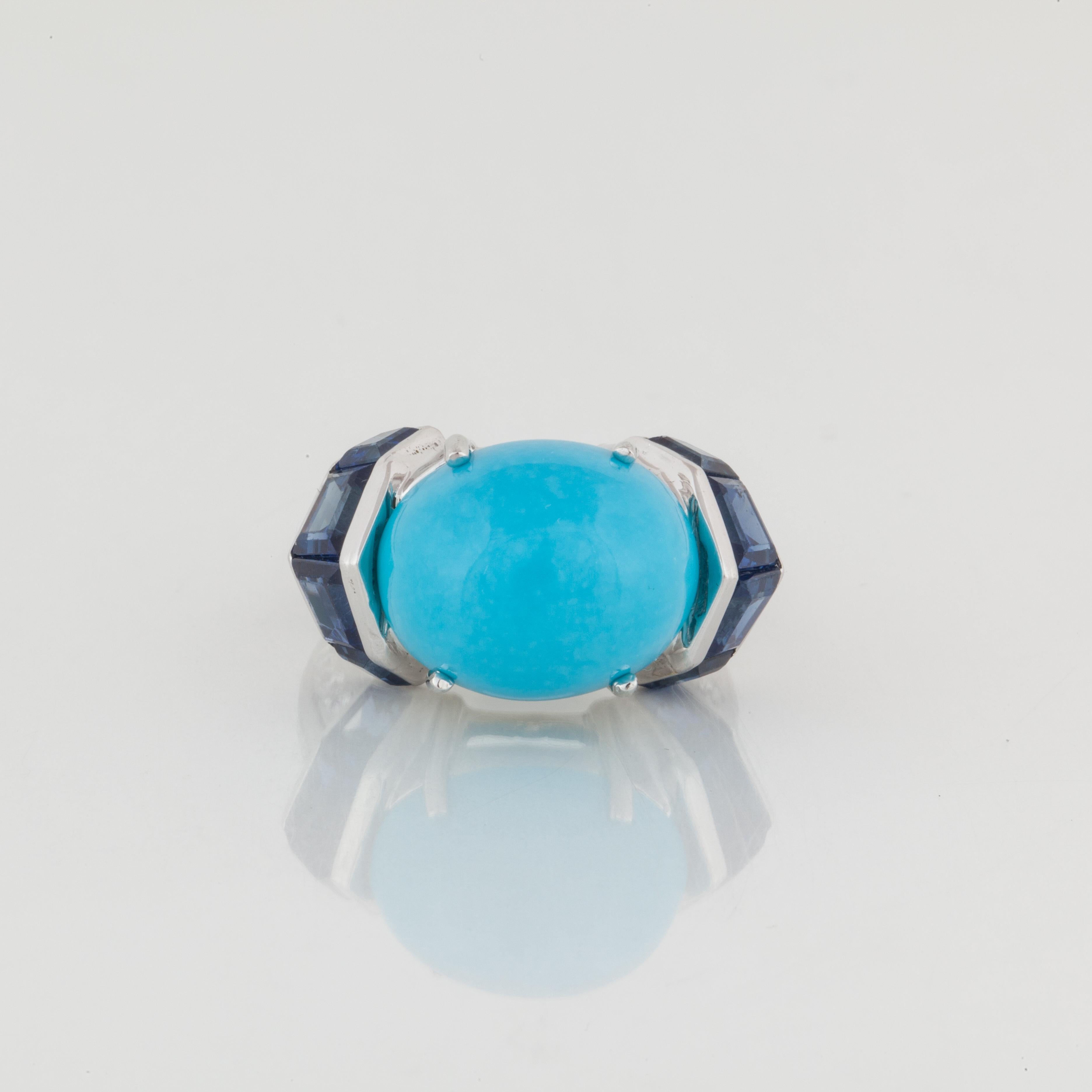 Platinum ring featuring a cabochon turquoise accented by calibré cut blue sapphires and diamonds. There are 12 round diamonds and 6 baguette diamonds with a total carat weight of 0.38; H-I color and VS clarity.  Presentation area is 1 inch by 1 inch