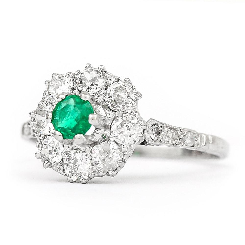 A pretty emerald & diamond vintage cluster ring made in platinum c.1950’s. Comprising a centre emerald of good colour est. 0.20ct with eight brilliant cut diamonds with an estimated 0.80ct weight surrounding the emerald all claw set. Also set with