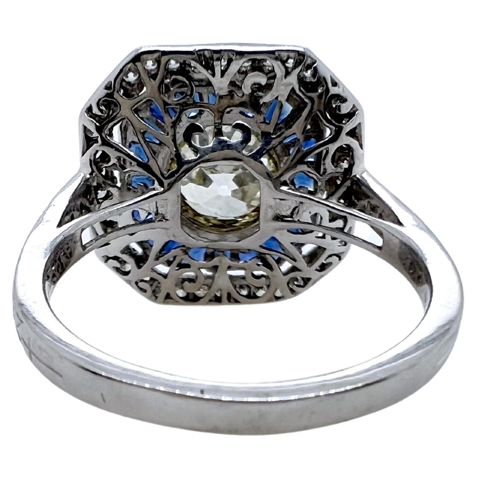 This gorgeous reproduction vintage style ring is set in platinum with a breathtaking old mine cut diamond.  The sapphire baguettes surround the bezel set diamond while the smaller round brilliant diamonds finish the setting.  This iconic looking