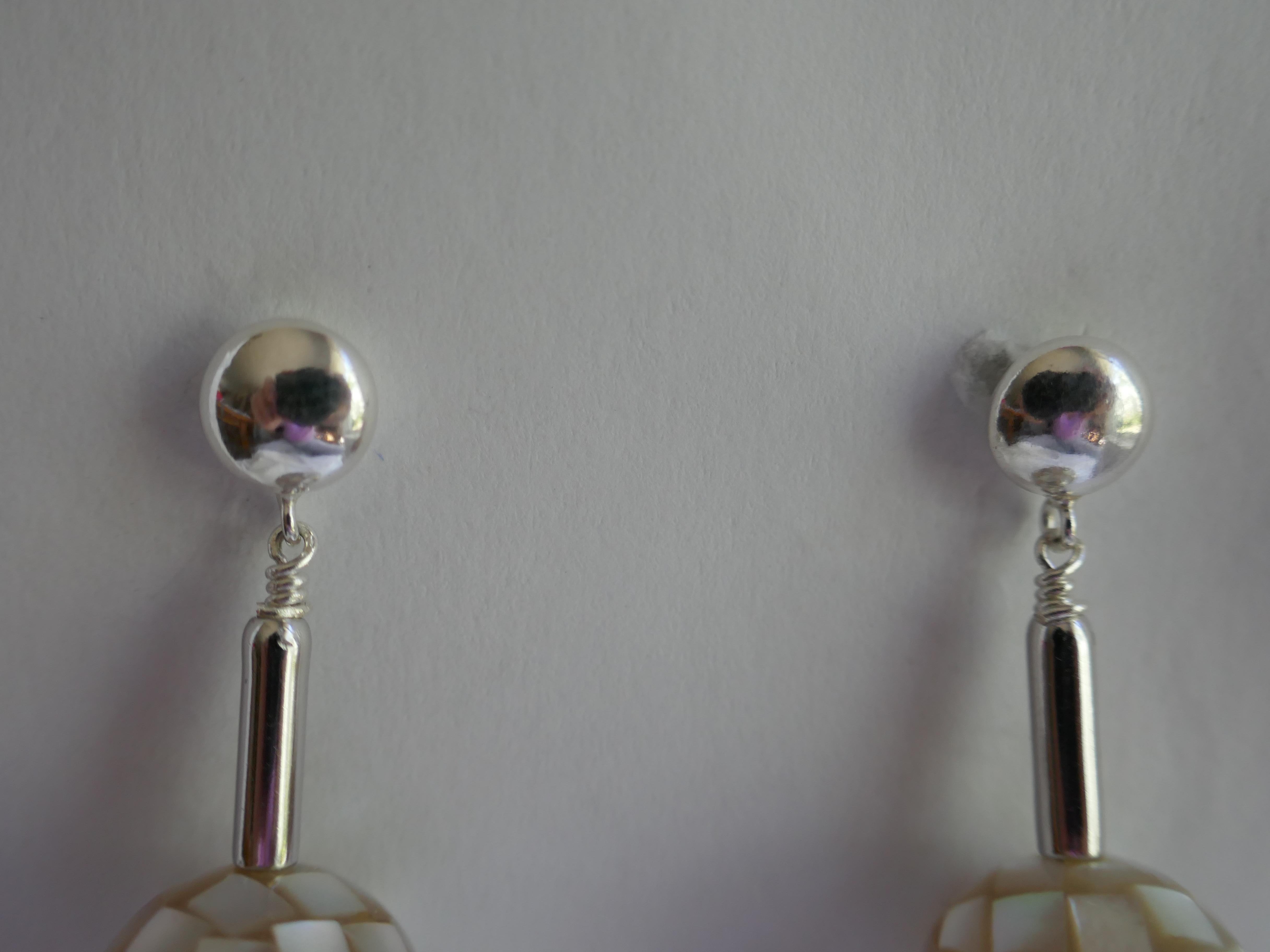 The earrings have 14mm platinum white mother of pearl beads that hang from 925 sterling silver tube and 7mm round post. The earring is 1 3/8 inches long. They look beautiful on. This is the pair you will be purchasing. Designed and created by Lucy
