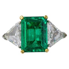 Anello a tre pietre in platino e oro giallo con smeraldo taglio smeraldo e diamante taglio trillion