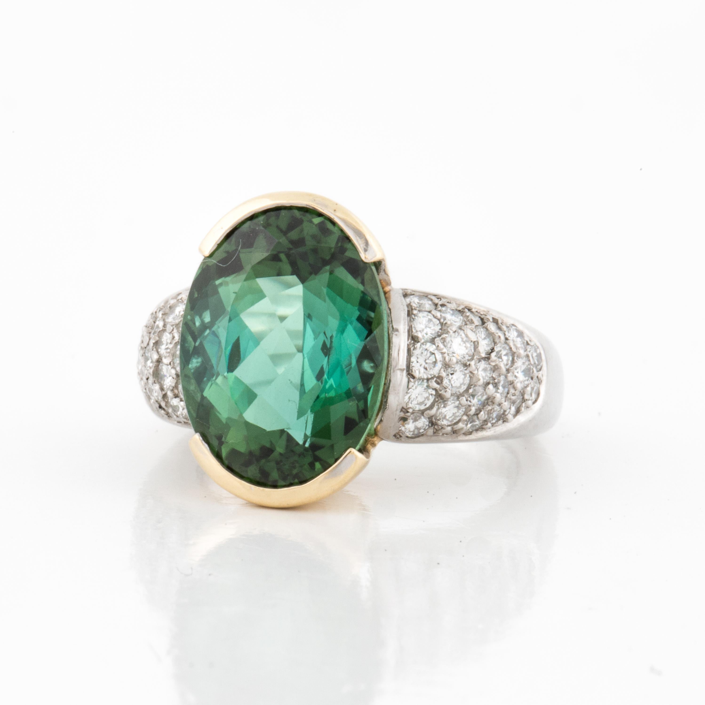 Vintage platinum ring featuring a 7.10 carat green tourmaline in an 18K yellow gold half bezel design.  Additionally there are 46 round diamond accents that total 1.35 carats, F-G color and VVS2-VS1 clarity.  Signed by Erwin Reu.  Circa 1990.  Ring
