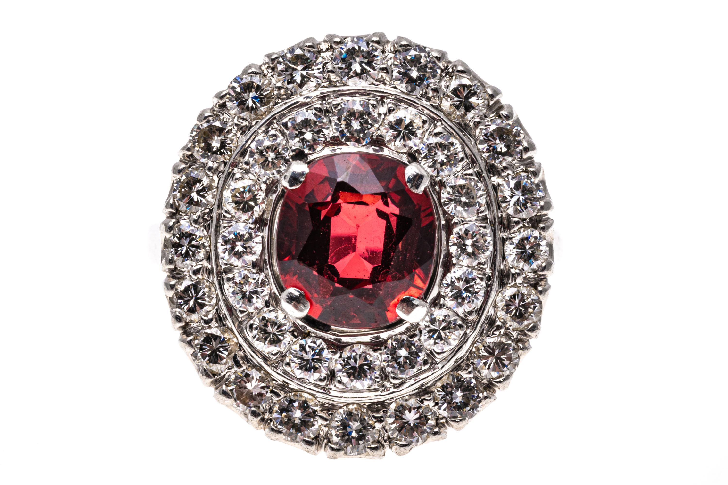 Platinum, Zircon And Diamond Double Halo Cocktail Ring, App. 0.92 TCW.
This gorgeous ring is a cocktail style, with a faceted oval shape, medium to dark red orange zircon center stone, prong set, and approximately 2.37 CTS. Surrounding the stone is