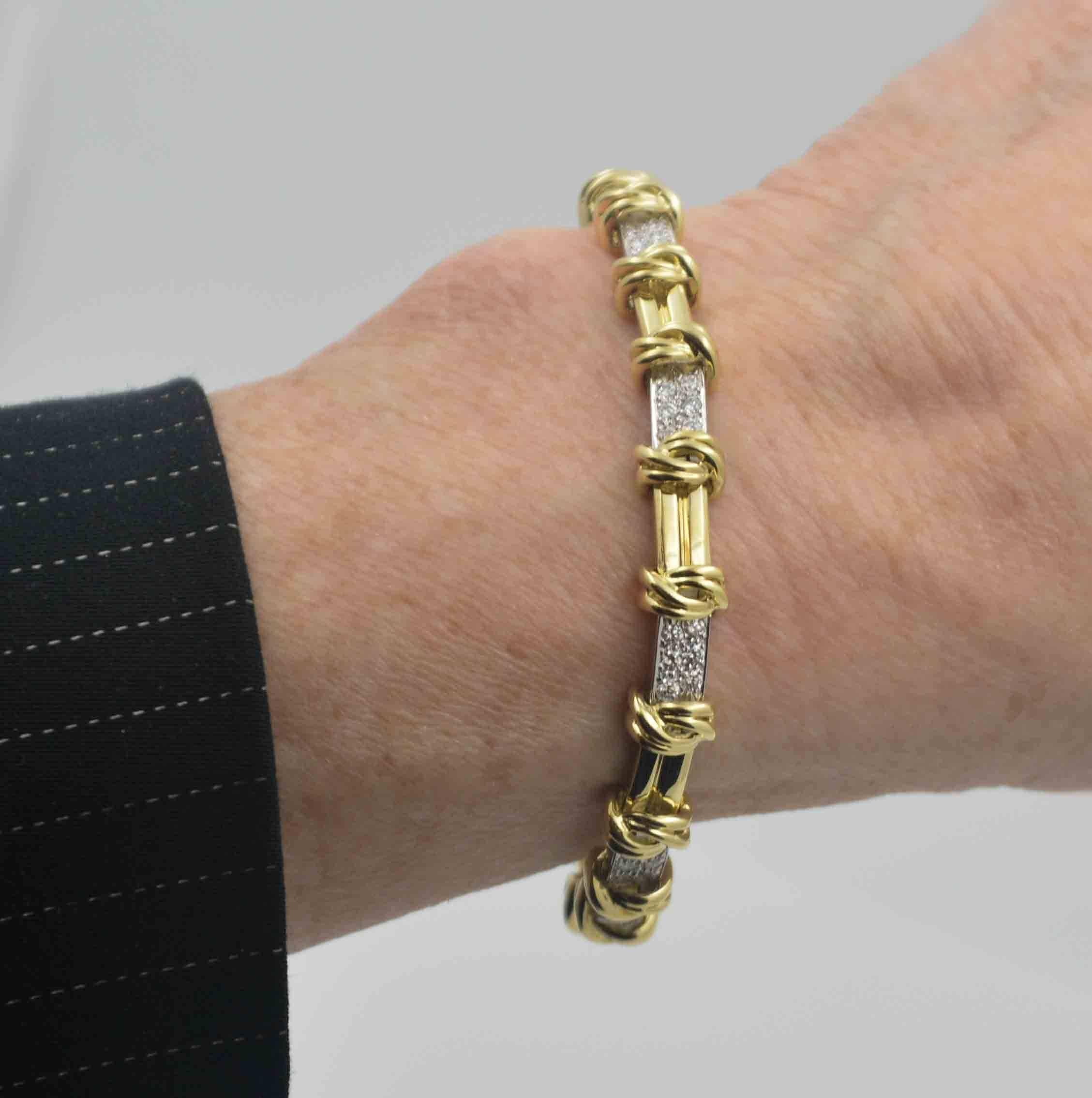Shimmering around your wrist is a stately platinum, 18 Karat yellow gold and diamond bar and knot link bracelet. This gorgeous bracelet measures 7 inches in length. 48 Round brilliant cut diamonds (1.00 carat, G-H color, VS internal clarity) pave