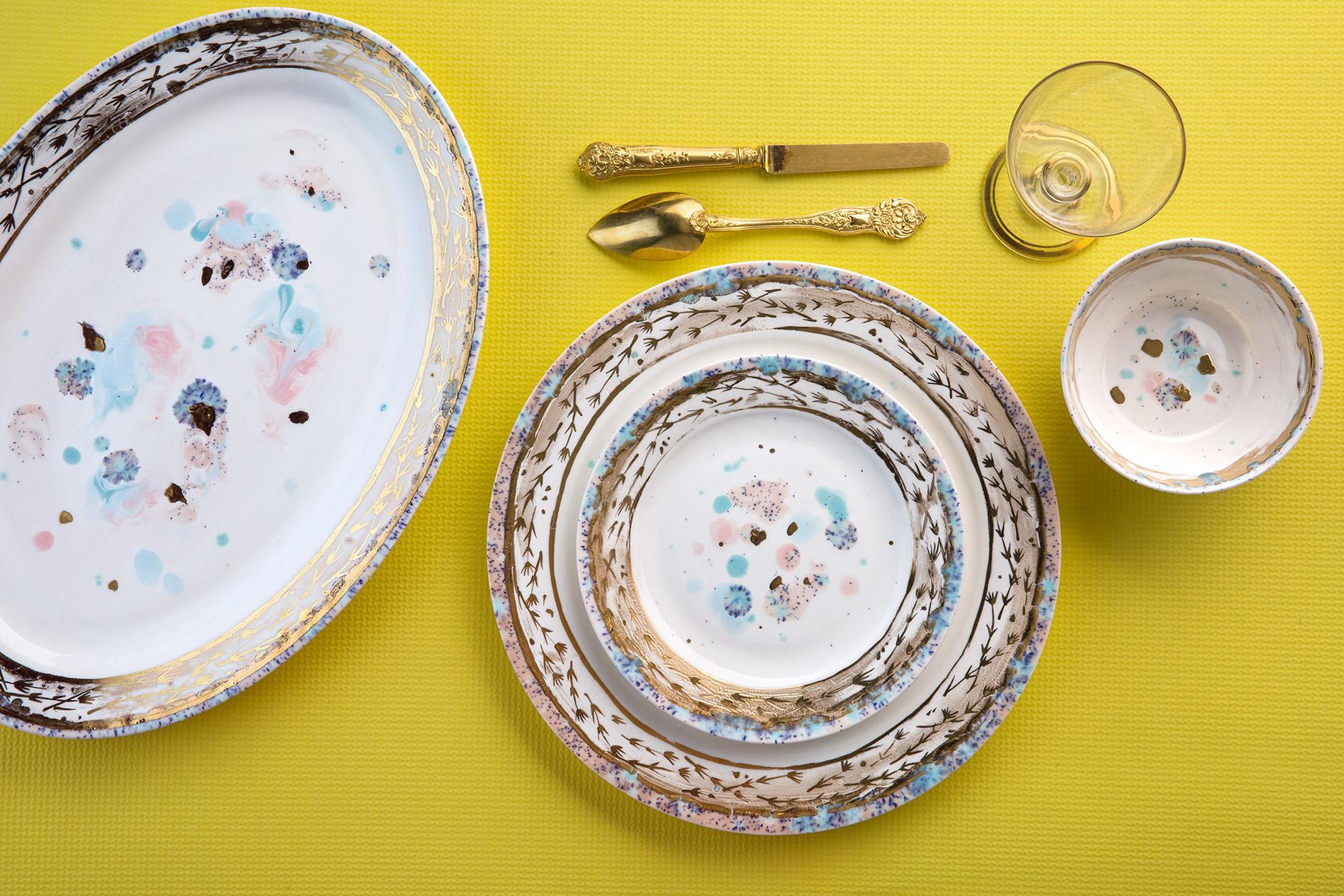 Hand painted in Italy from the finest porcelain, this Dafne Rim Platter has a narrow pink and blue dotted rim surrounding a broad, delicate golden decor of stylized flowers; subtle light blue and pink brushes sprinkled with black powder float on the