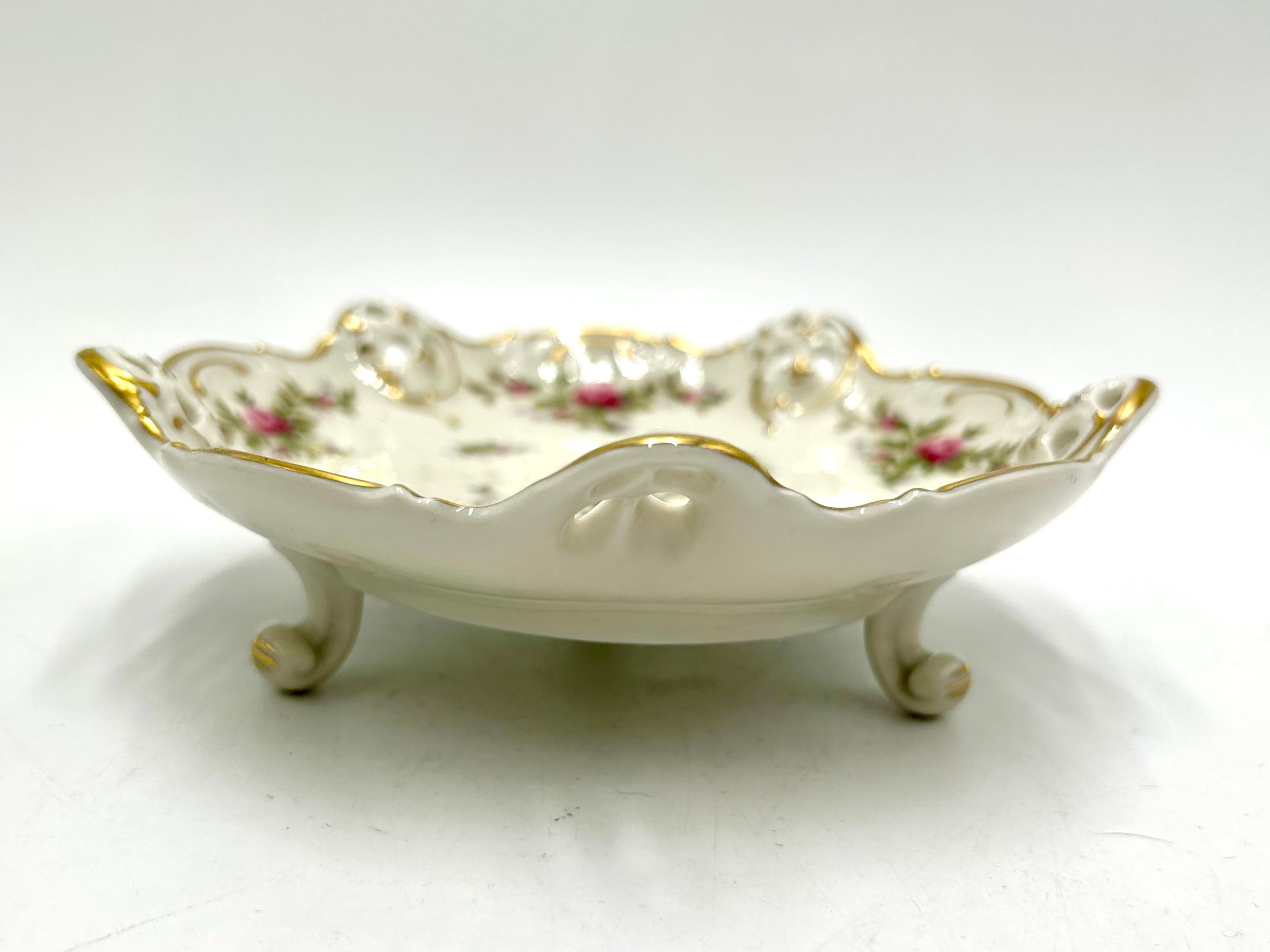Openwork plate supported on three filigree legs from the Moliere collection, the renowned German Rosenthal label. The product is marked with the mark used in the years 1938-1952. Porcelain in ecru color decorated with openwork sides, rose motif and