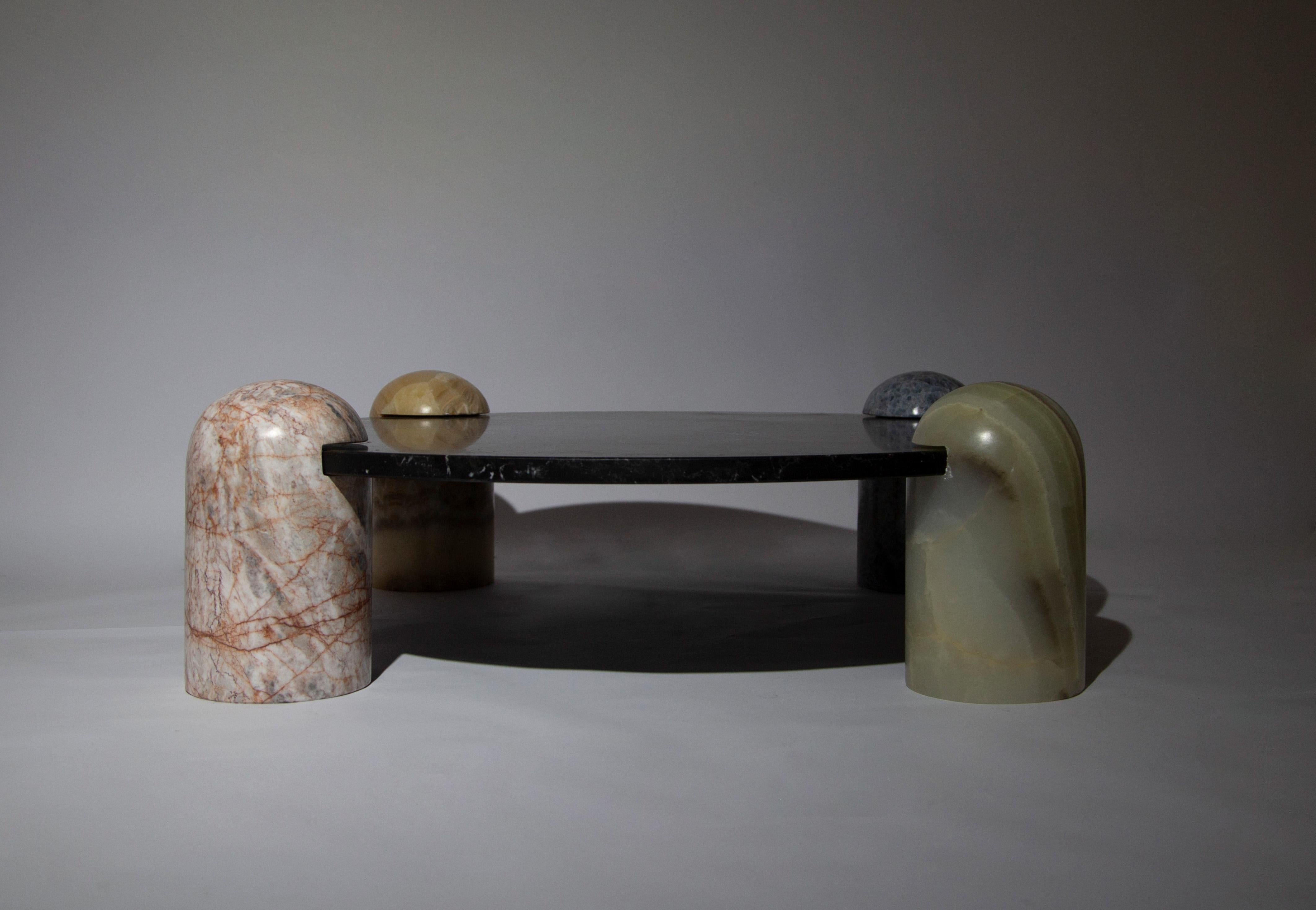 Rounded pillars of blue calcite, pink marble, caramel onyx and green onyx carry a black marble top to create  Play-time Table; An elegant rendition of children’s furniture. A piece meticulously hand-sculpted from stones endemic to Mexico. The