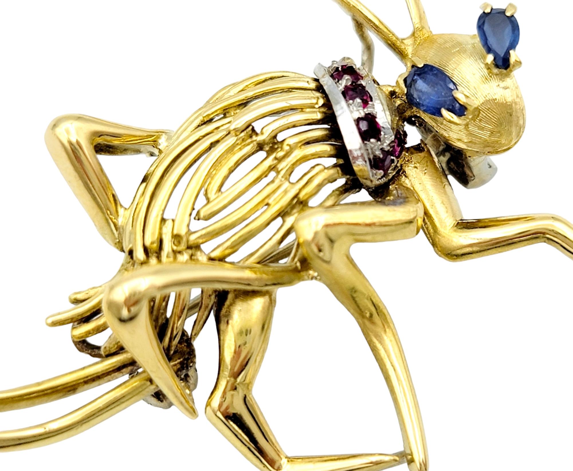 This unique cricket brooch is a dazzling piece made with the timeless appeal of 14 karat yellow gold. The focal point of this brooch is its captivating sapphire eyes. These pear-shaped sapphires, carefully chosen for their deep, velvety blue hue,
