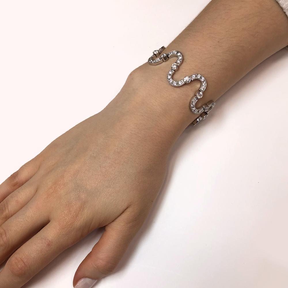 Flirty and playful contemporary bracelet.
Adorned with white round cut diamonds 9.35 carat total, and covers a stylized curving and twisting parts of platinum 950 metal. 
Diamonds are all natural in G-H Color Clarity VS.
Length: 20 cm
Width. 1.9