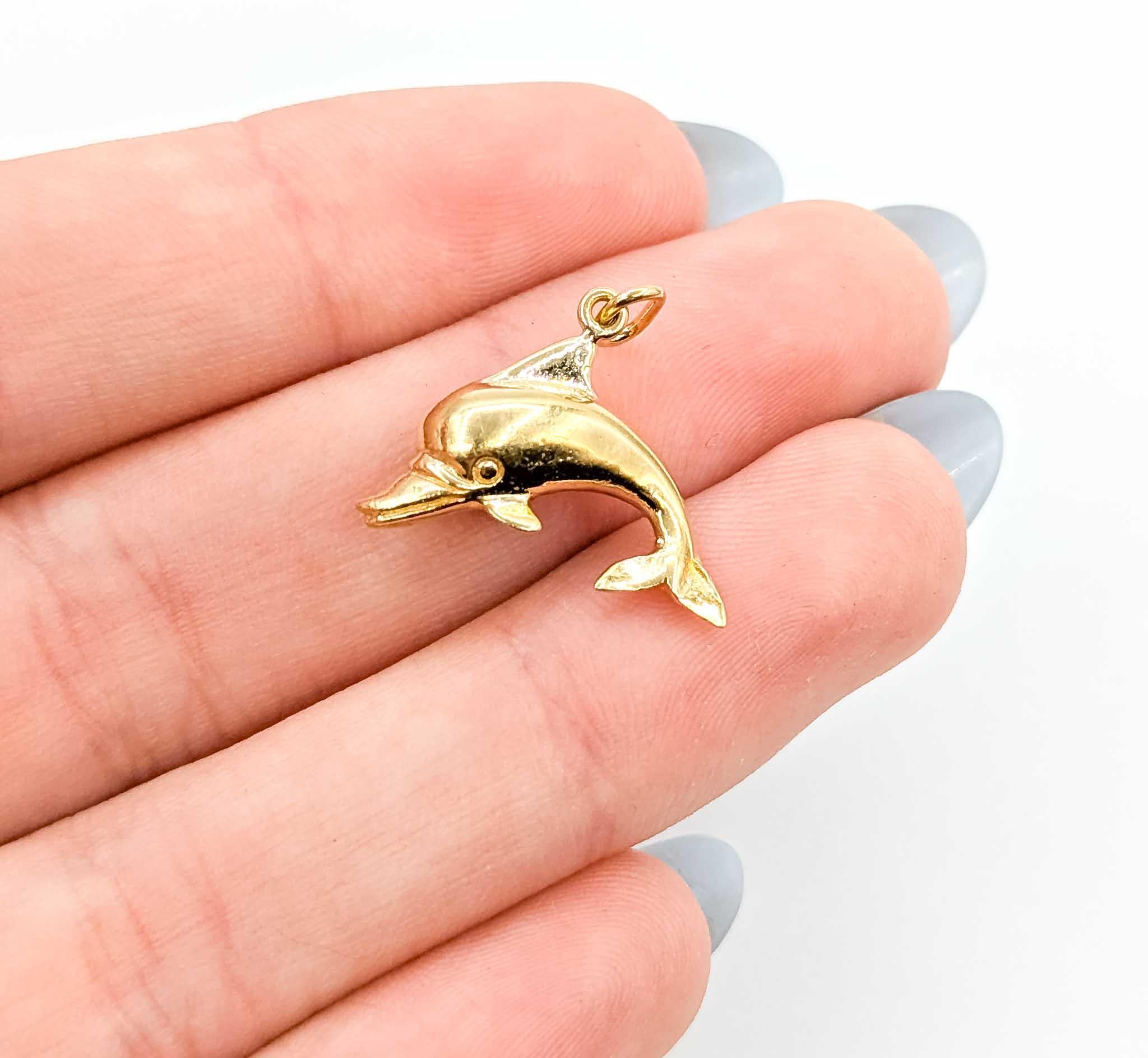 This charming pendant is crafted in 14k yellow gold and designed in the shape of a playful dolphin, symbolizing joy, freedom, and harmony with the sea. Measuring 19.75 x 17mm and weighing 4.87 grams, it offers a substantial presence while