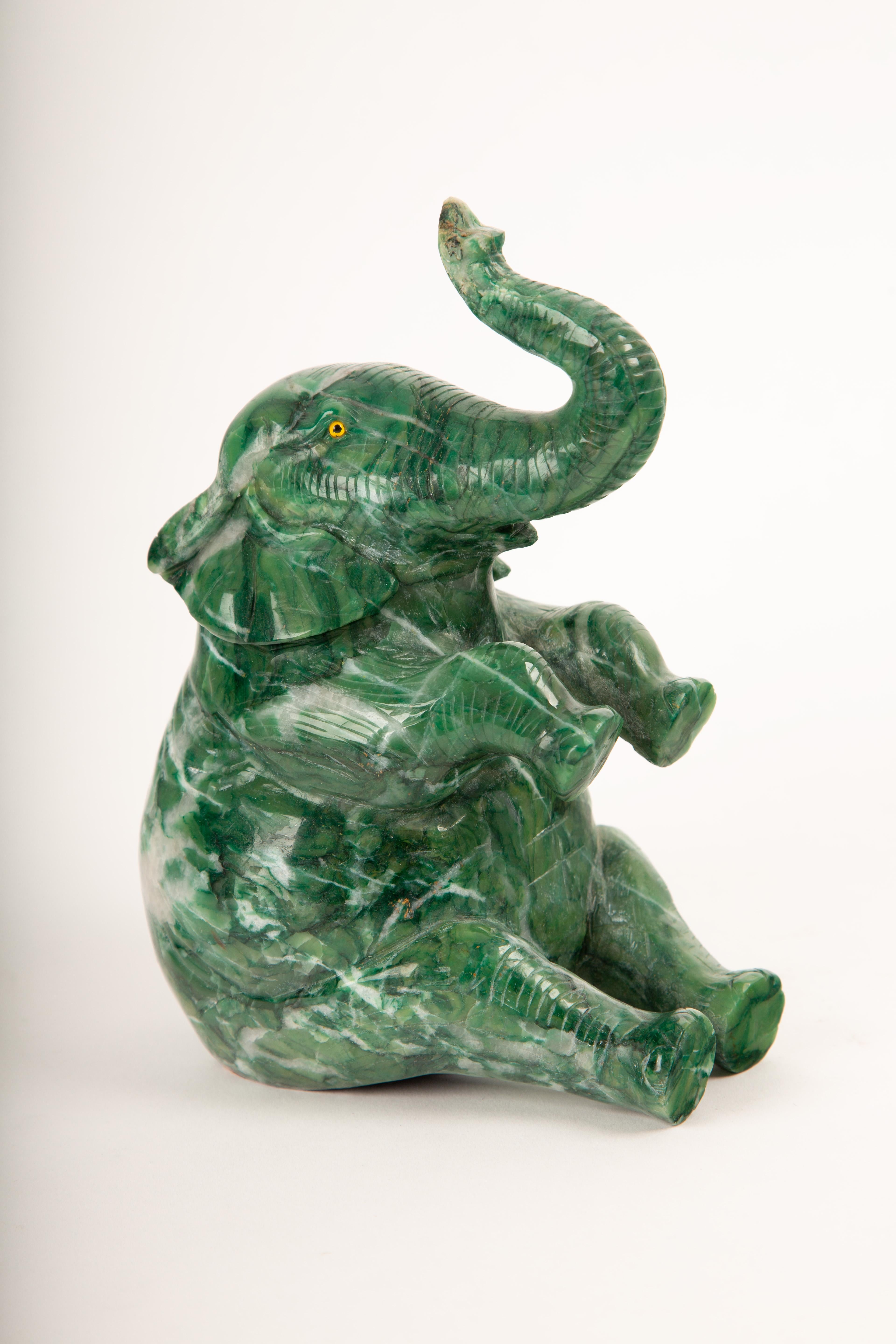 Cet éléphant fantaisiste et magnifiquement sculpté est taillé dans une riche agate mousse verte, une pierre semi-précieuse prisée pour ses variations naturelles et sa translucidité terreuse. Mesurant 7,75 pouces de haut, l'éléphant est représenté