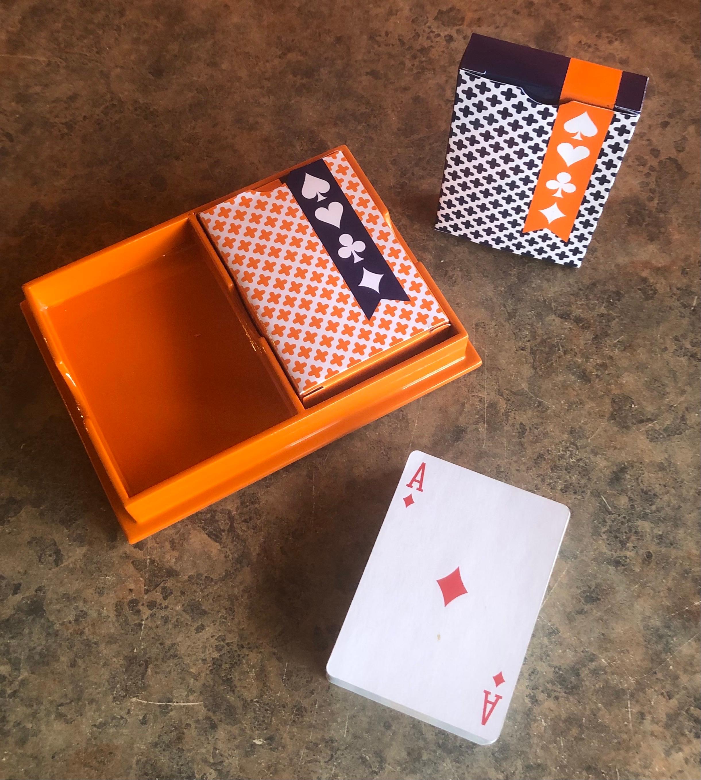 Very cool bright orange plastic case with pin stipes and two decks of playing cards by Jonathan Adler, circa 2000s. #1336.