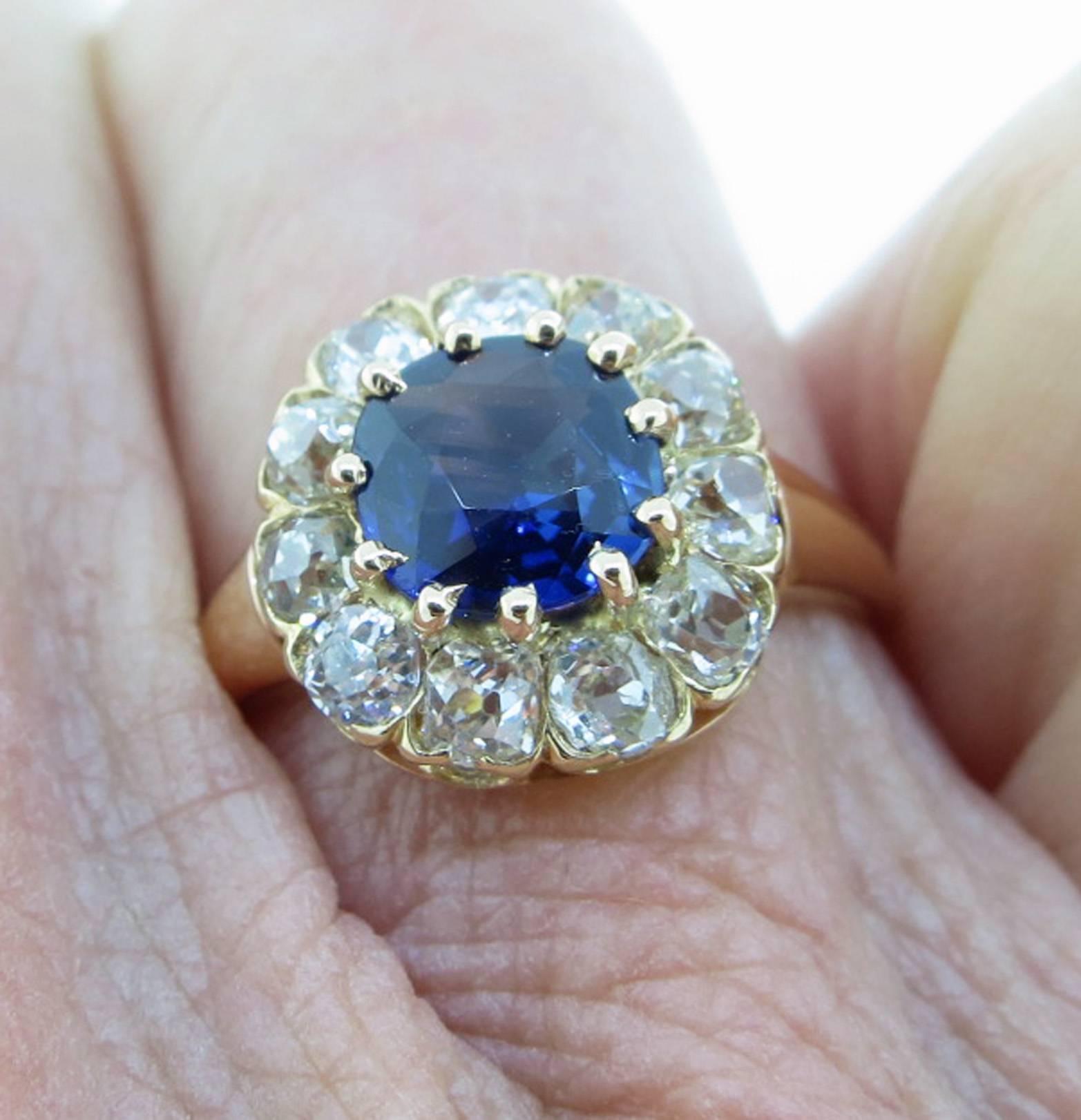 14kt. yellow gold sapphire and diamond cluster ring, the center is set with a natural blue faceted sapphire weighing approx 1.0ct. surrounded with 11 old cushion cut diamonds totaling approx  .70cts. grading VS clarity I color. The ring is size 6