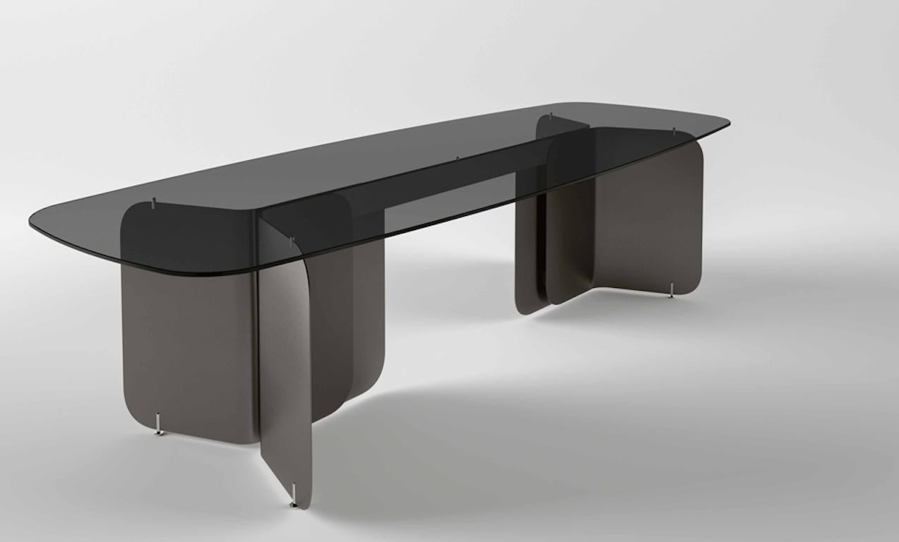 Die Wahl der Oberflächen für die Platte und das Untergestell zusammen mit der Harmonie der Formen ergibt einen Tisch mit perfekten Proportionen und umhüllendem Stil. Die Idee eines dünnen, gefalteten Papiers entwickelt sich zu einem Gefühl von